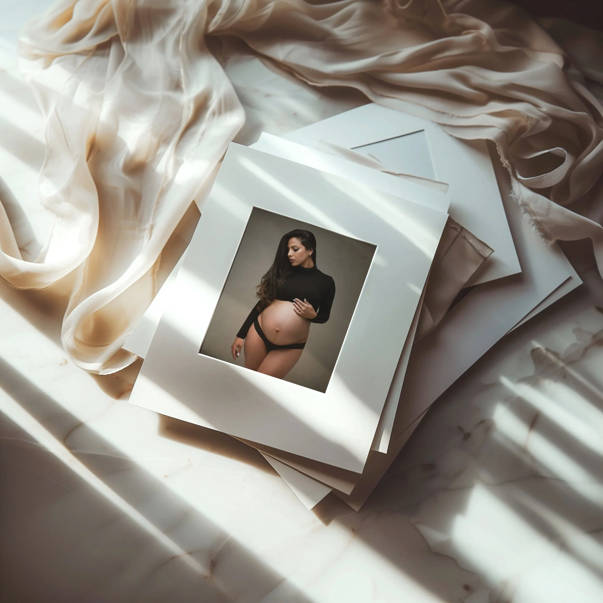 A stack of photographs on marble surface, featuring a pregnant woman in black lingerie and a black top. soft light and shadows create a warm, intimate atmosphere.