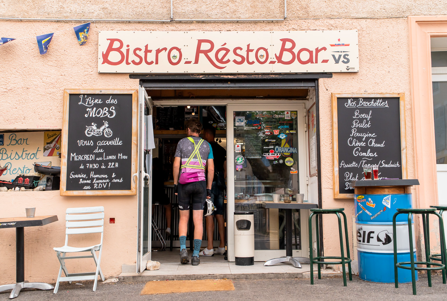 Ciclistas de la Race Across France descansan en un bistró local, símbolo de las paradas auténticas y amistosas en el ultraciclismo.