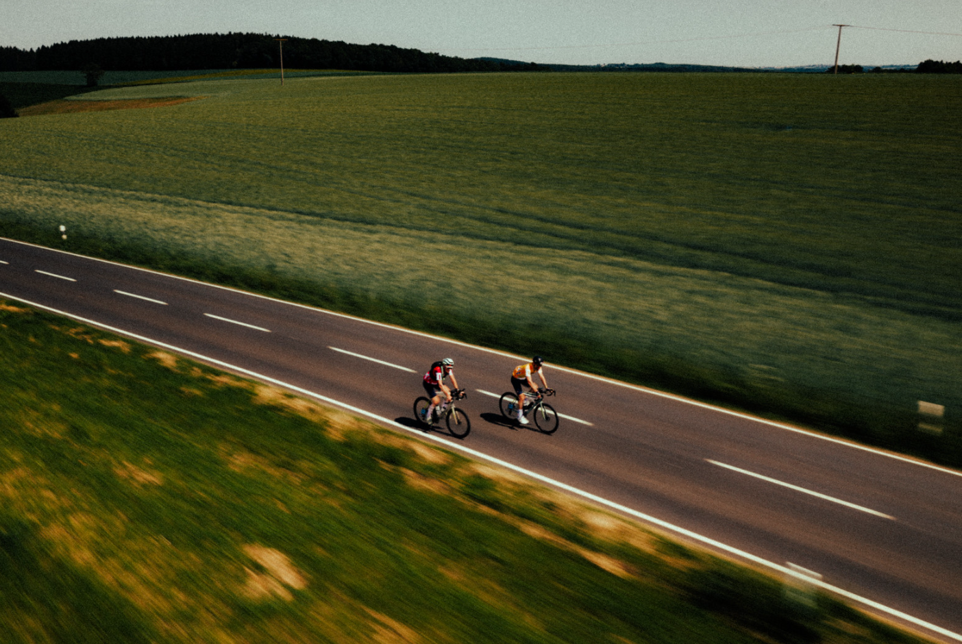 Deux cyclistes pédalant sur une route entourée de végétation.