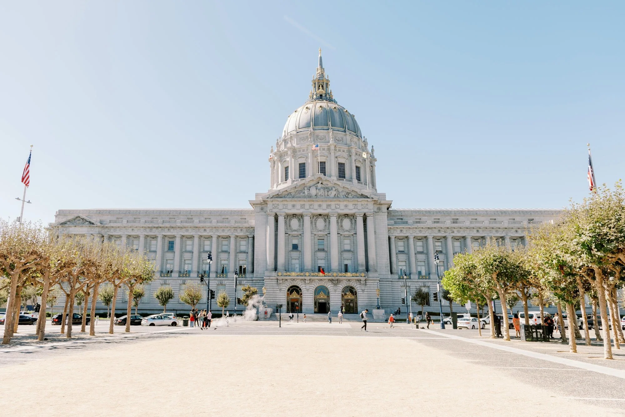 The California State Capitol building in Sacramento with a clear blue sky and a few trees in the foreground.