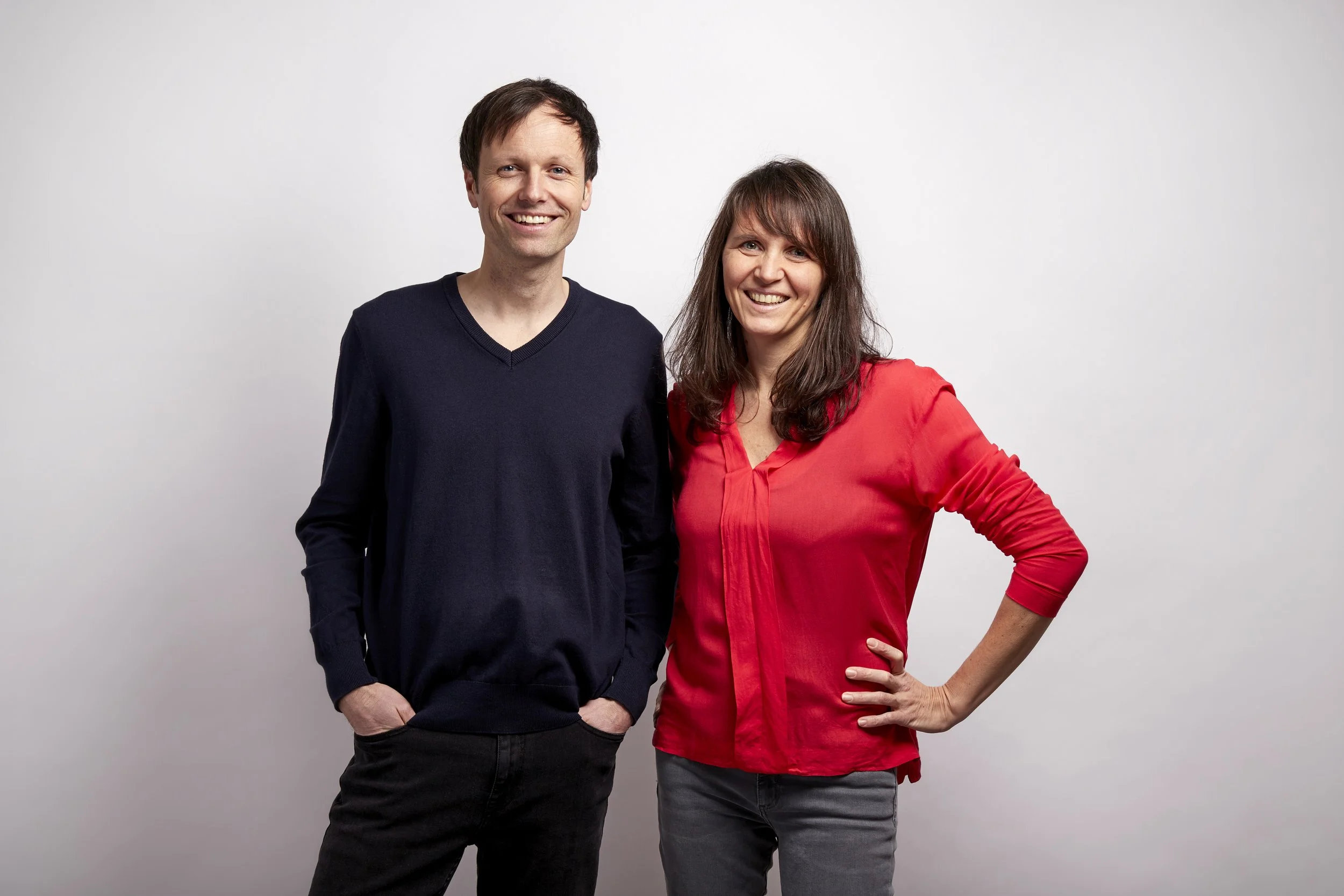 Transformationsbegleitung. Hannes und Dagmar Horn. Ein Mann und eine Frau stehen nebeneinander vor einem weißen Hintergrund und lächeln in die Kamera.