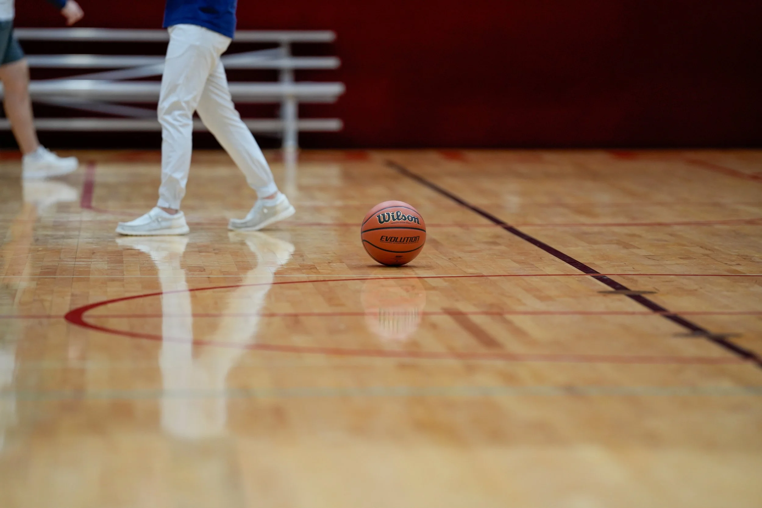 A basketball on the court with players standing nearby.