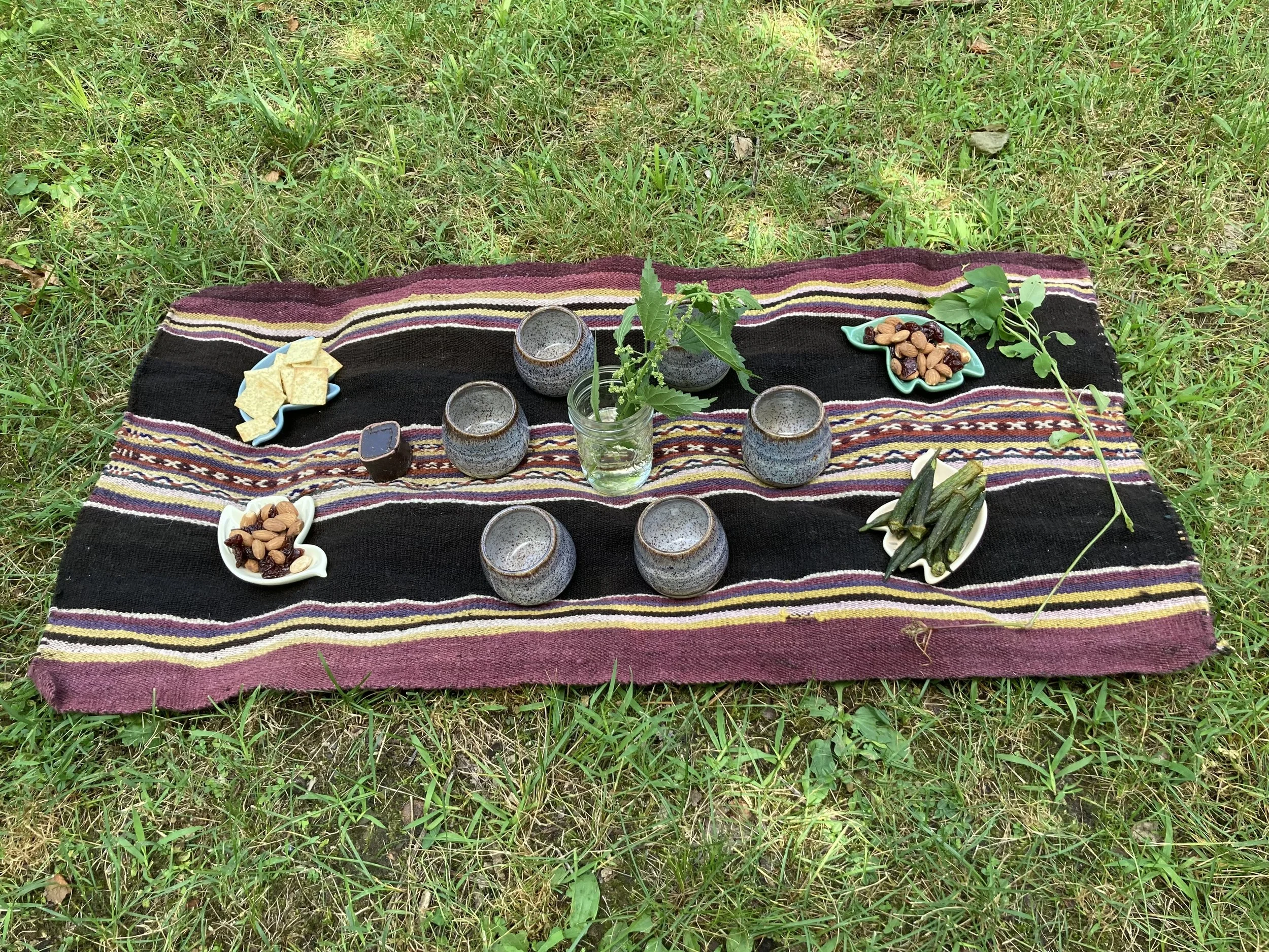 Stinging nettles in vase surrounded by teacups and snacks