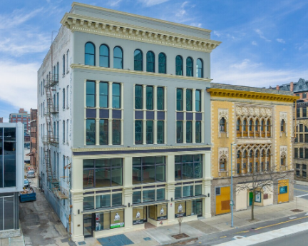 Street view of a multi-story historic building with large windows in an urban area.