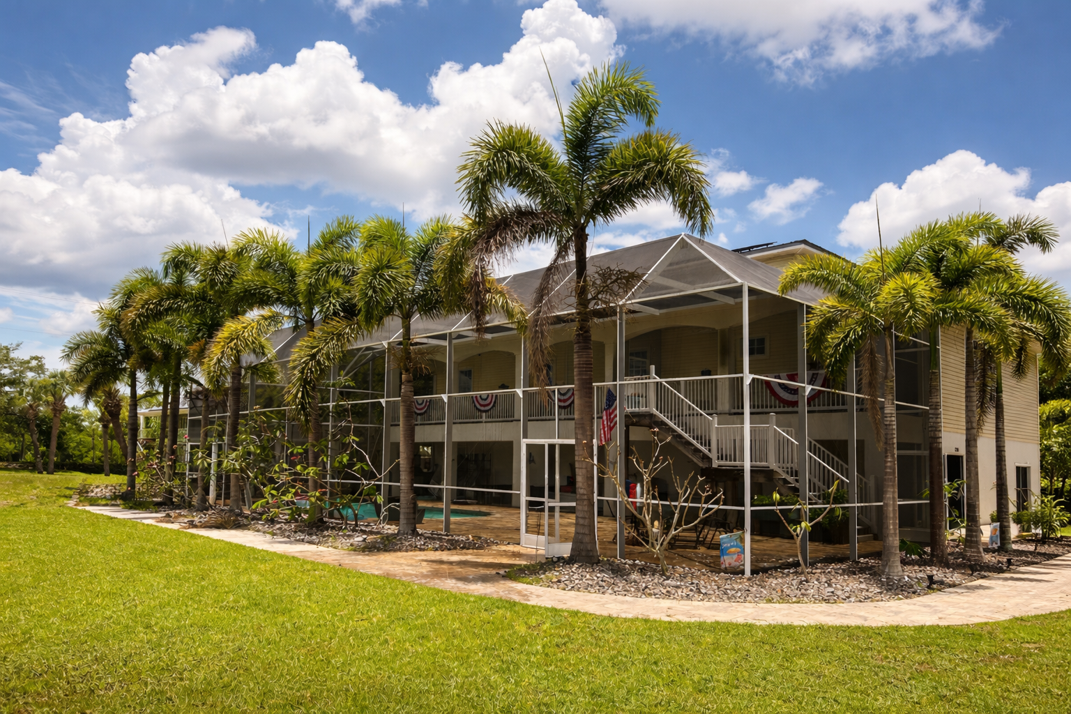Two-story Florida home with a white screened pool cage surrounded by palm trees under a sunny sky.