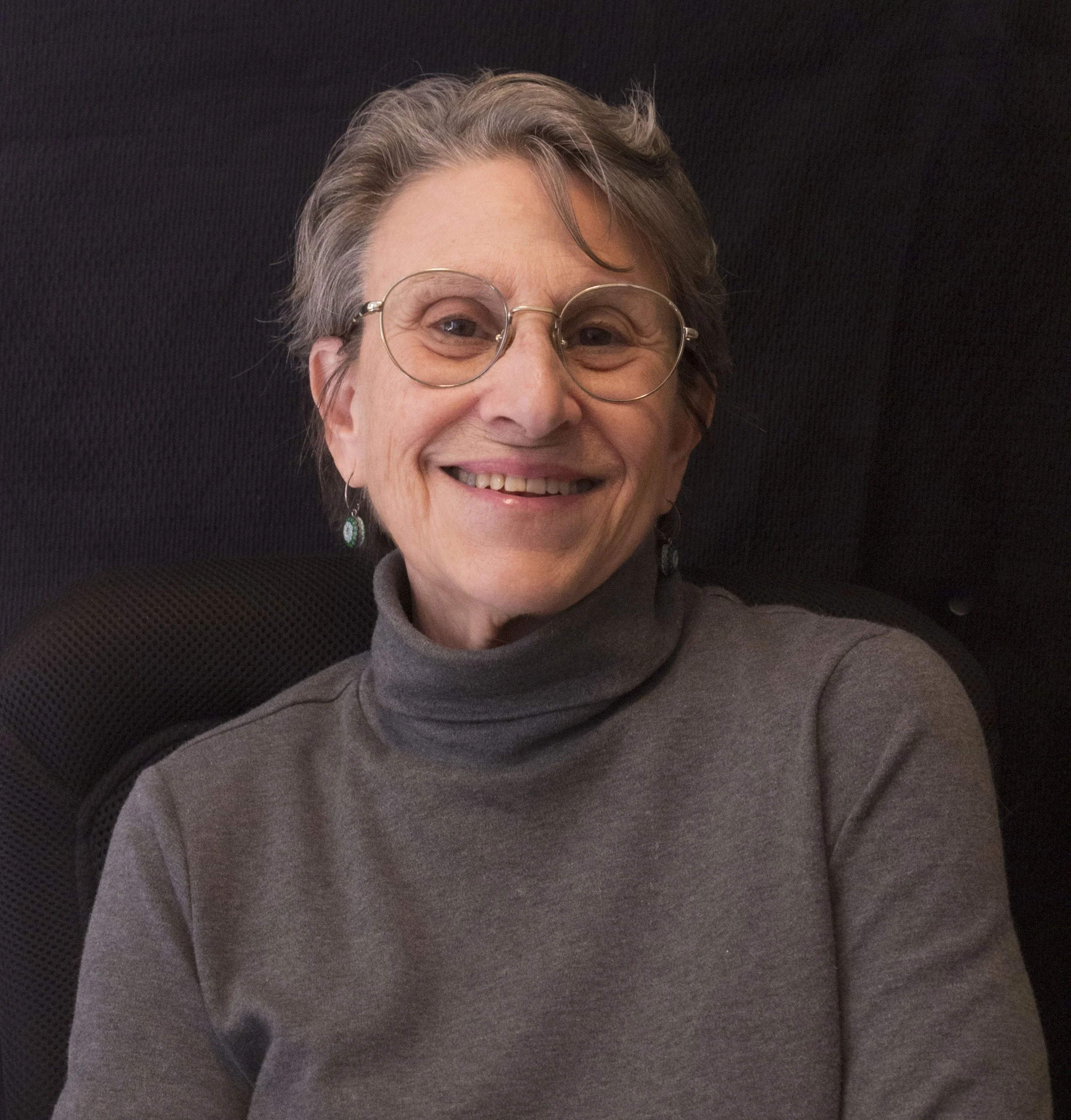 Portrait of photographer Andrea Zinn wearing a dark gray turtleneck and smiling blissfully