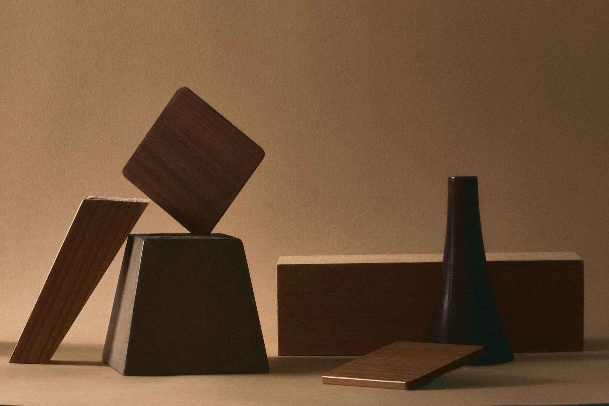 Minimalist arrangement of various geometric wooden and ceramic objects on a neutral background.
