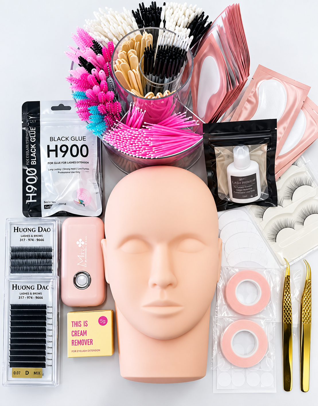 Professional eyelash extension supplies including lash trays, adhesive, tweezers, brushes, under-eye pads, tape and mannequin practice head.