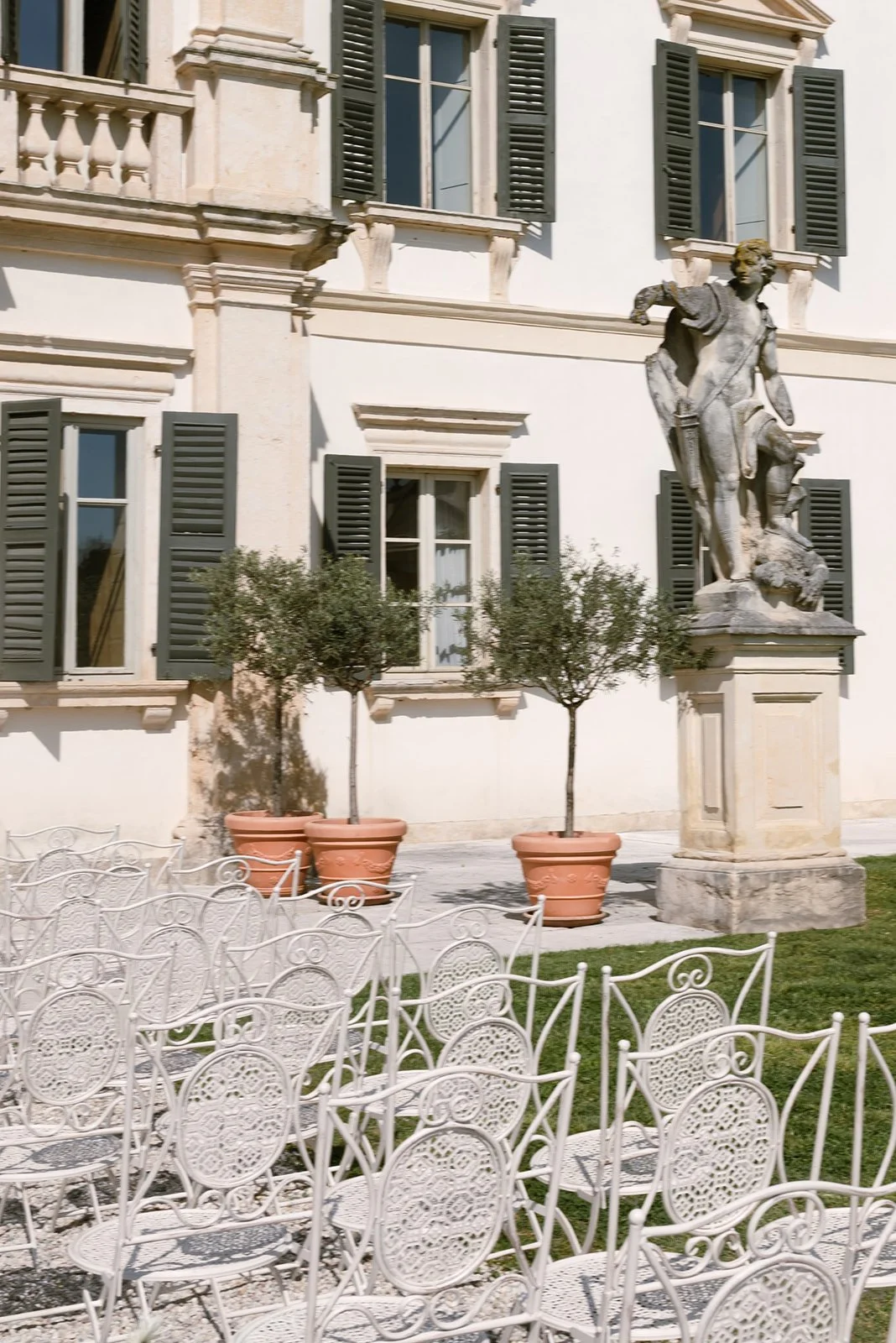 Fassade der Villa mit Statue und Stuhlreihen im Garten