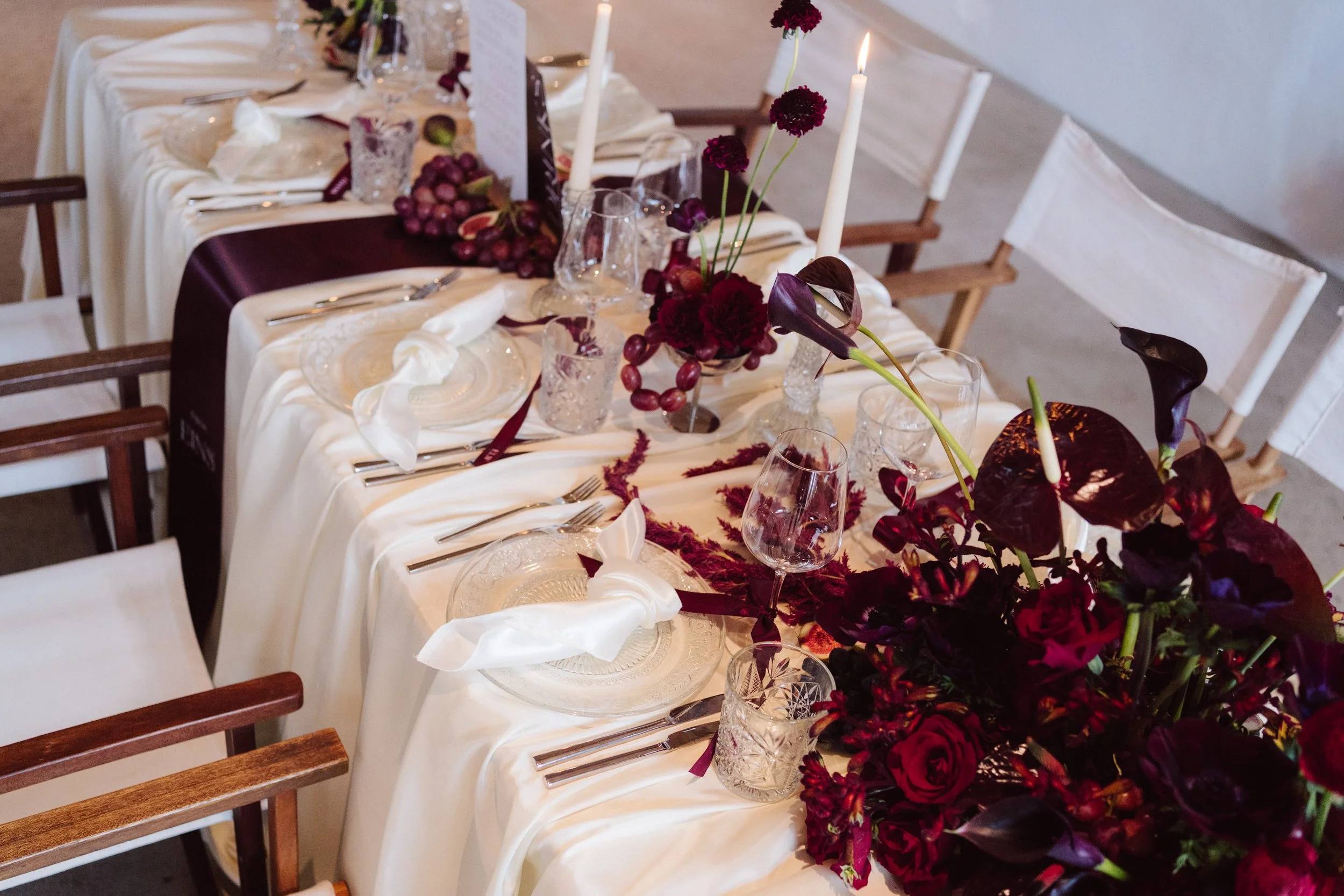 Lange Hochzeitstafel mit weinroter Blumendekoration auf Gut Mönkhof