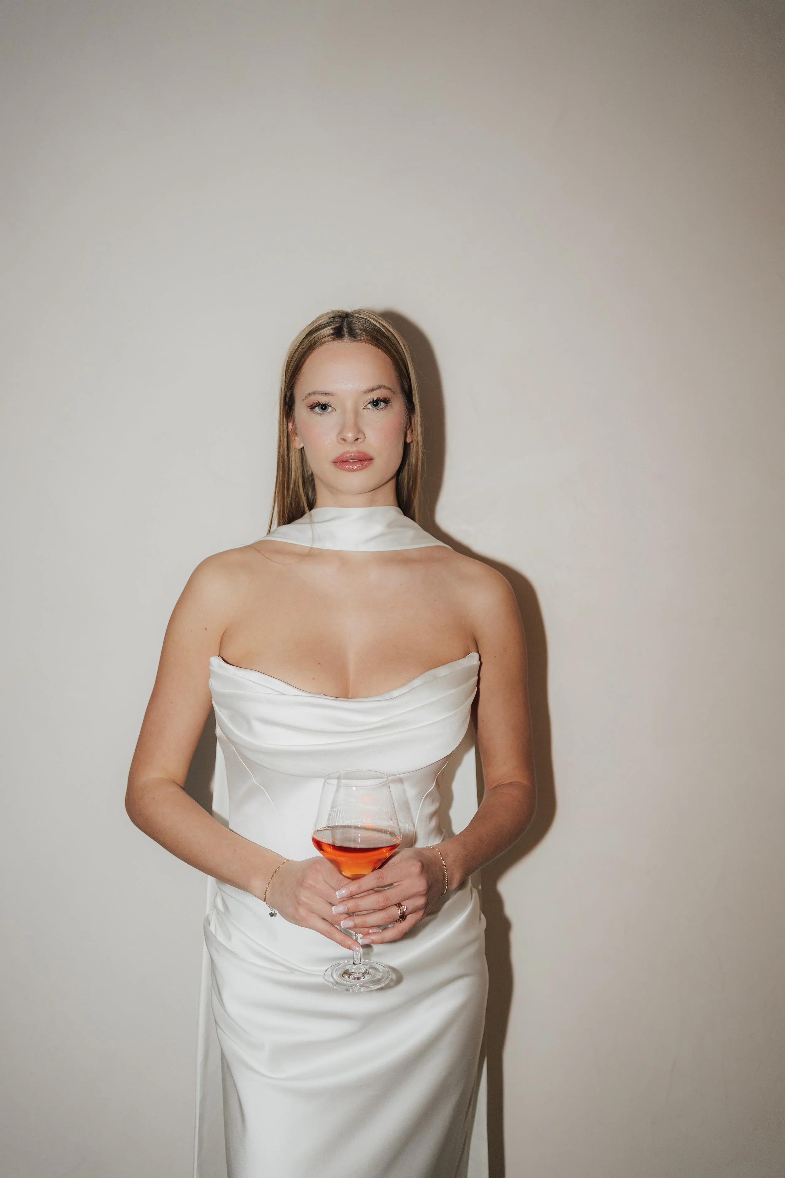 Braut mit Glas in der Hand im Seidenkleid