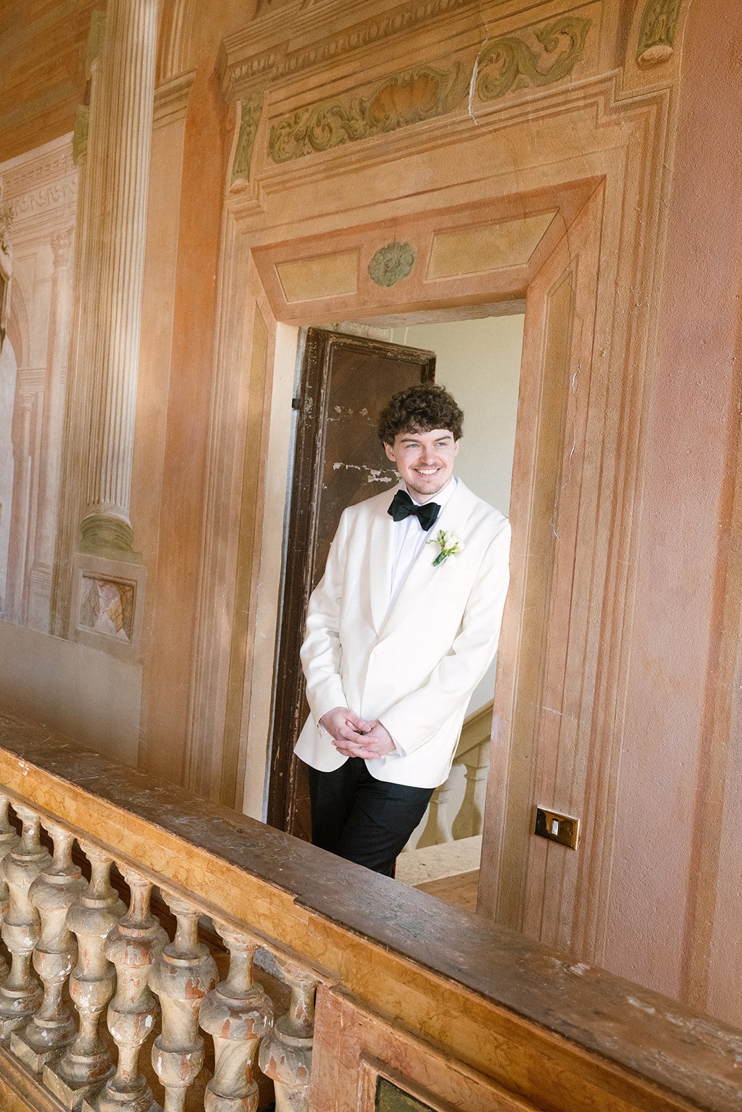 Bräutigam im weißen Dinnerjacket in der holzvertäfelten Halle der Villa