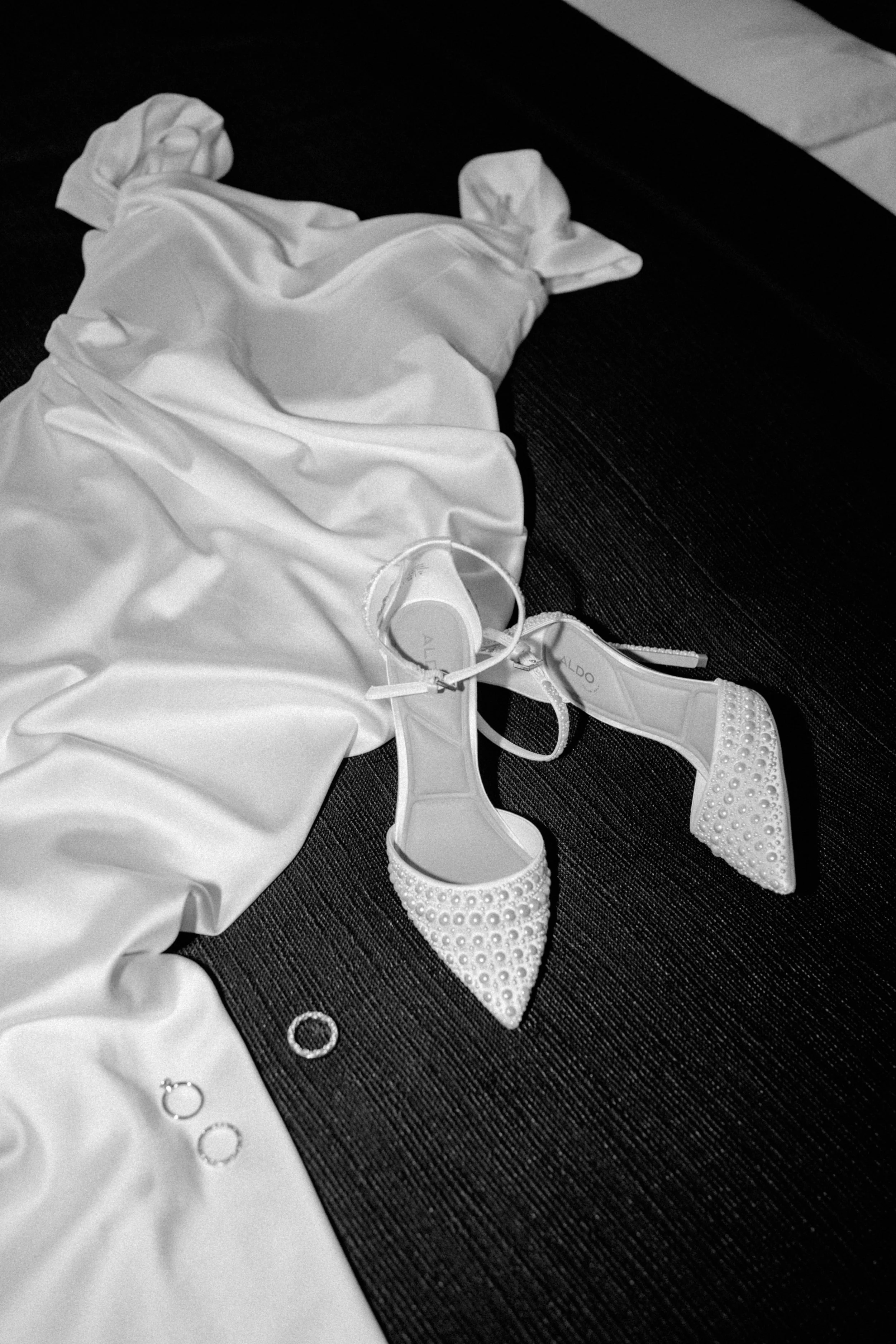 Brautschuhe mit Schleife und Eheringe auf dem Seidenkleid