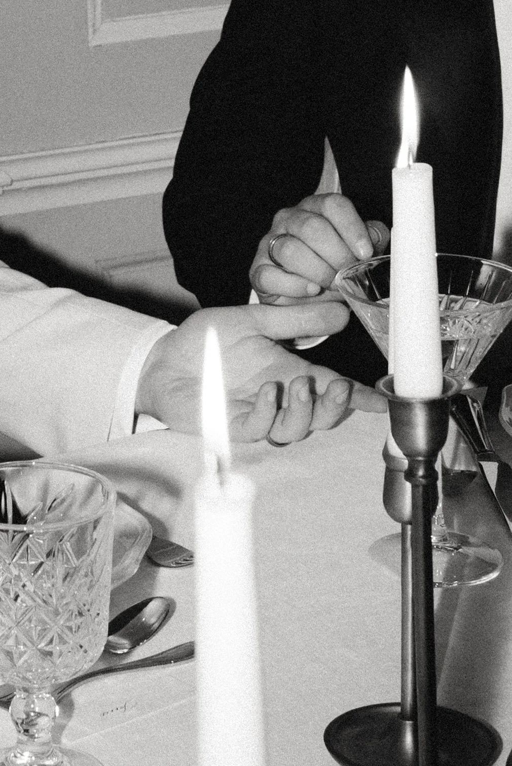 Zwei Hände neben einer brennenden Kerze auf der Tafel