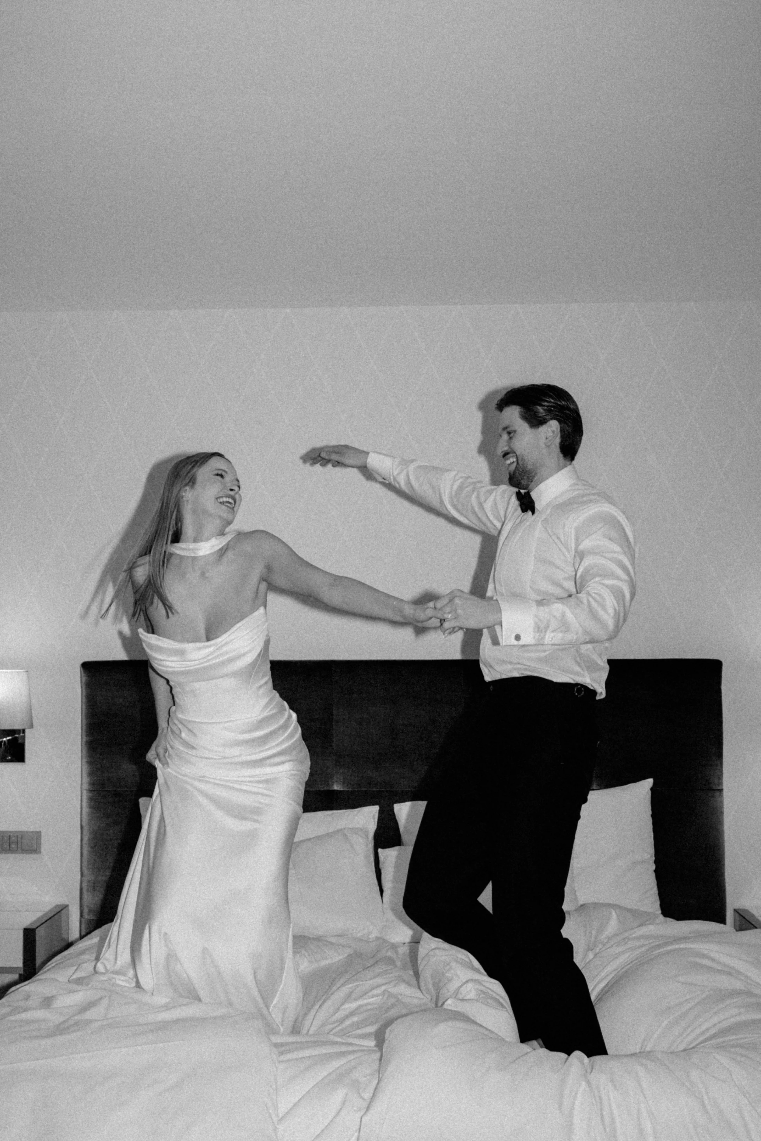 Brautpaar tanzt auf dem Bett der Hotelsuite