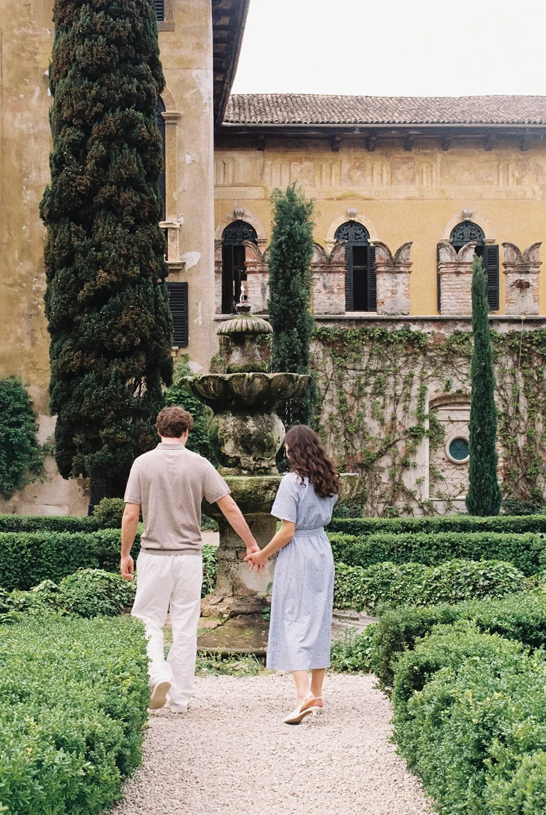Brautpaar läuft Hand in Hand durch den Garten der Villa