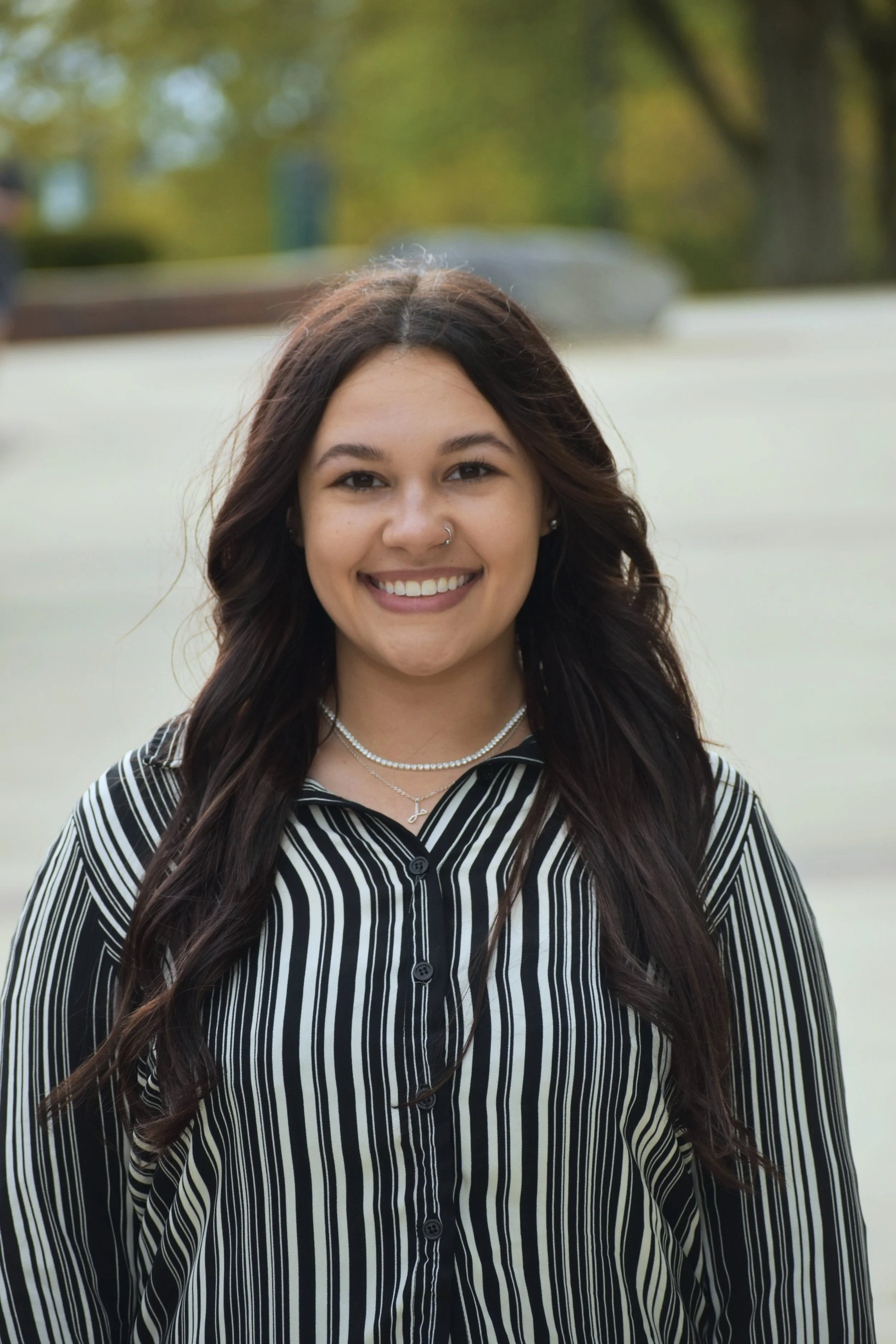 A pink upholstered armchair with black wooden legs in front of a pink wall, decorated with a bunch of blue balloons hanging overhead.