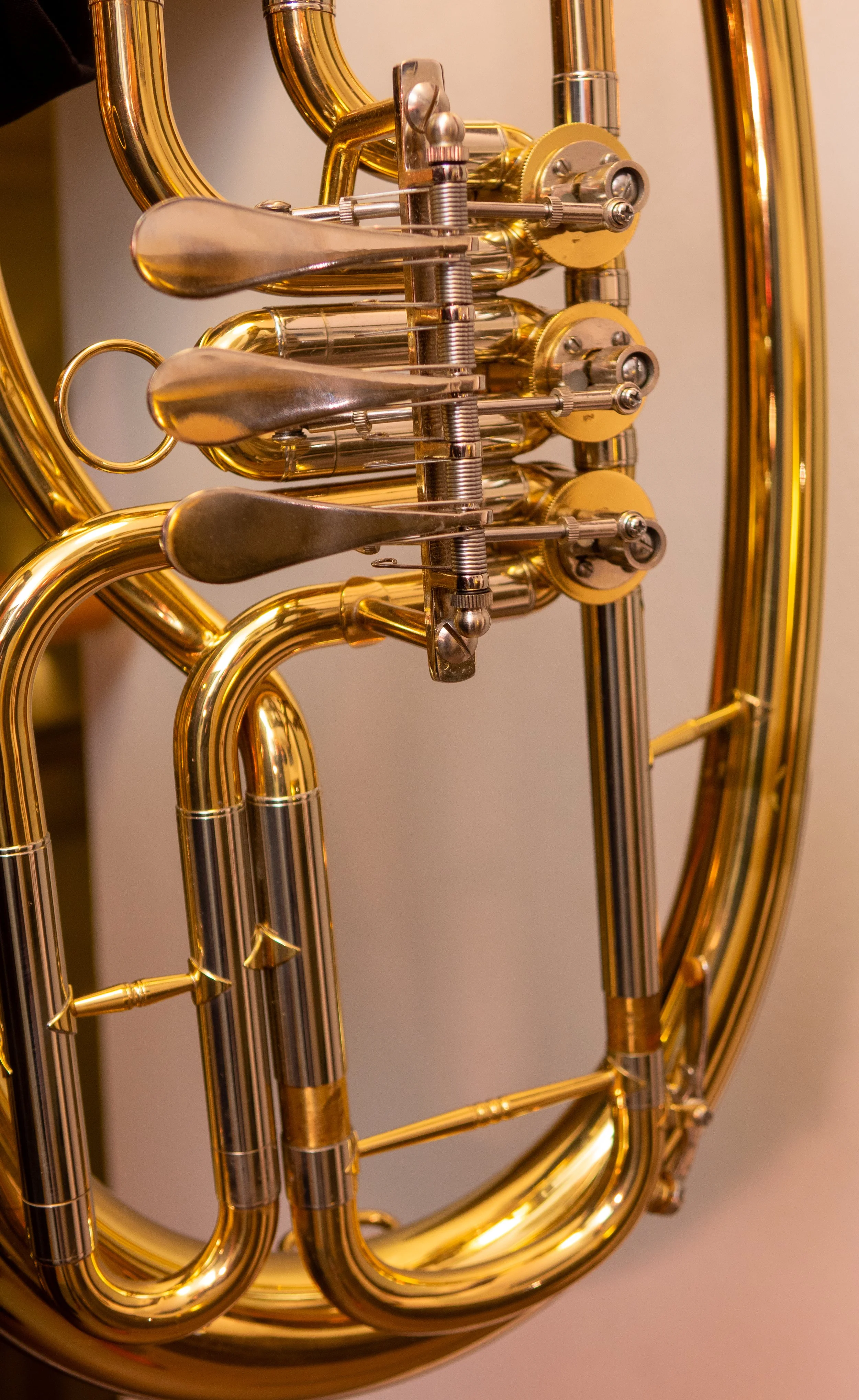 Detaillierte Nahaufnahme eines goldenen Blechblasinstruments mit Ventilen, vermutlich eine Tuba oder ein Euphonium.