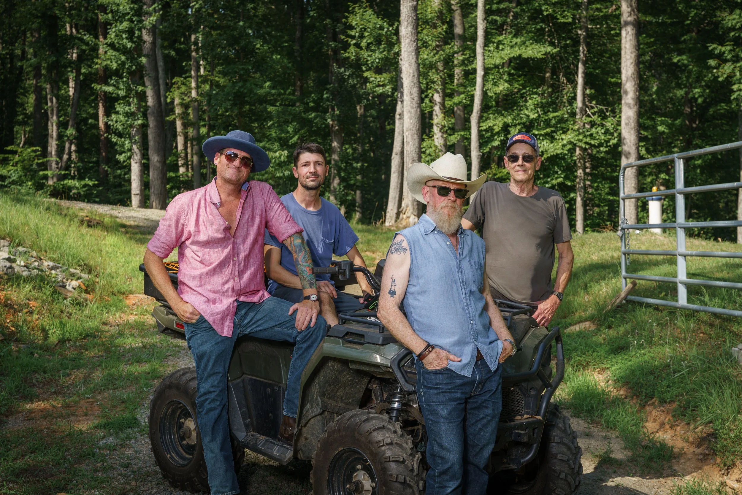 The 10-4 Good Buddies at Buck Naked Hunt Camp, with some sitting on an ATV and others standing next to it. They are wearing casual clothing including hats and sunglasses.