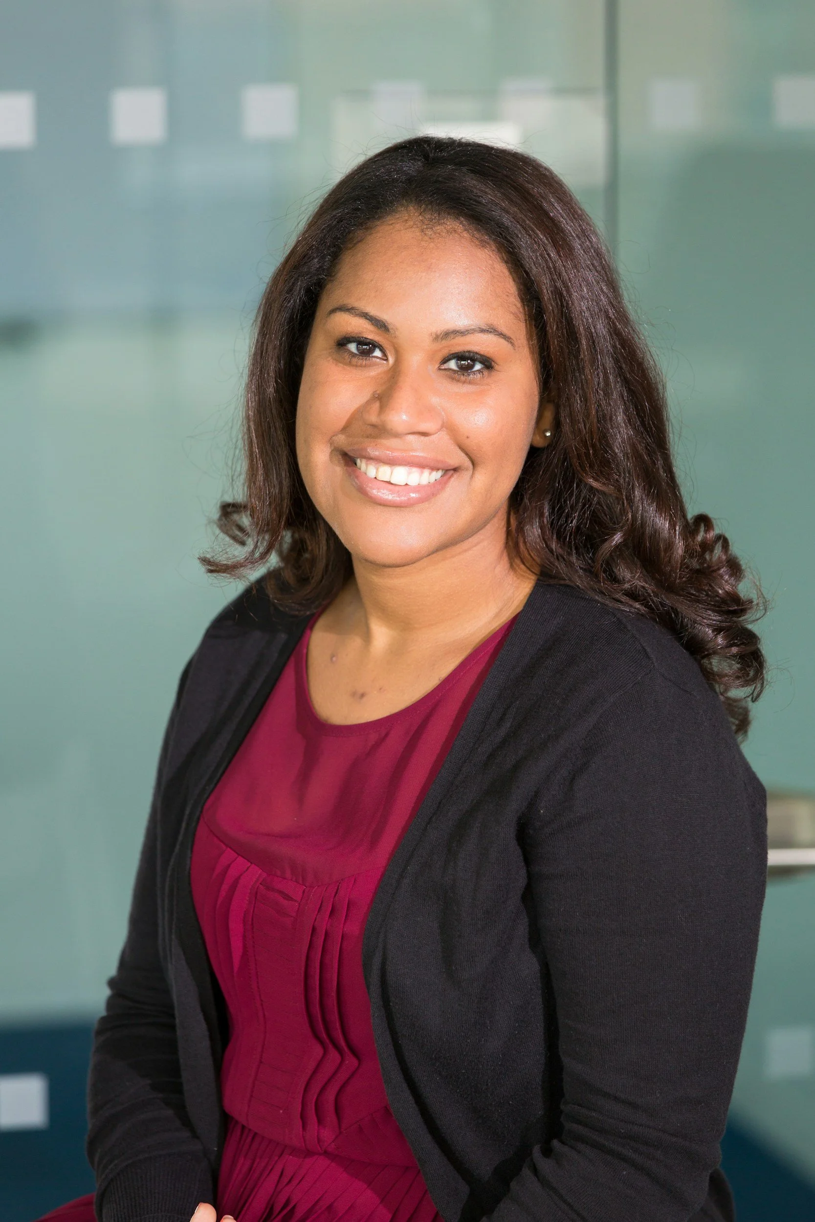 Smiling woman in maroon dress with black cardigan.
