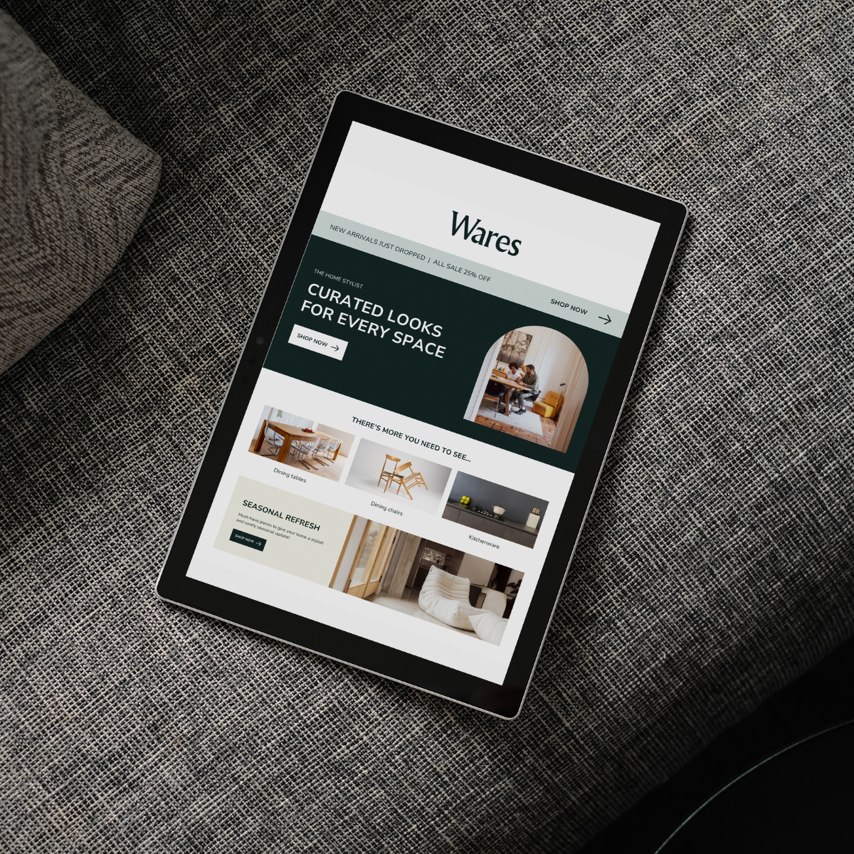 A tablet displaying a furniture website with categories like dining tables, dining chairs, and kitchenware, placed on a textured gray fabric surface.