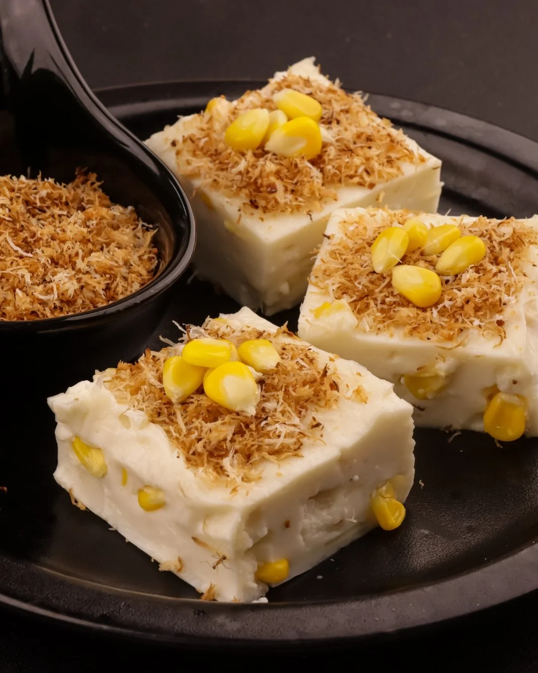 A half-eaten caramel topped cheesecake on white parchment paper, with a slice served on a white plate in the background.