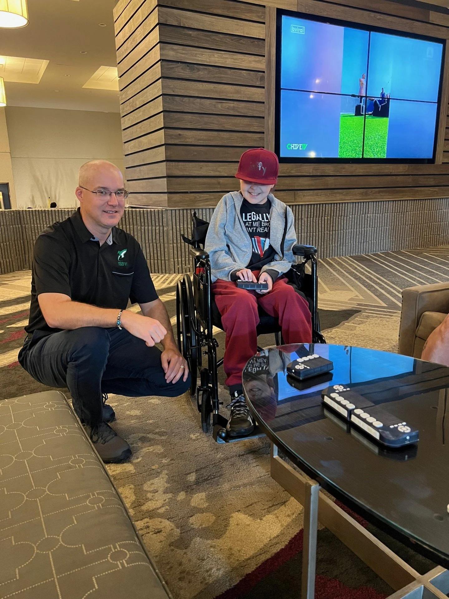 Photo of Carson sitting in his wheelchair, playing Cadence games with his friend.