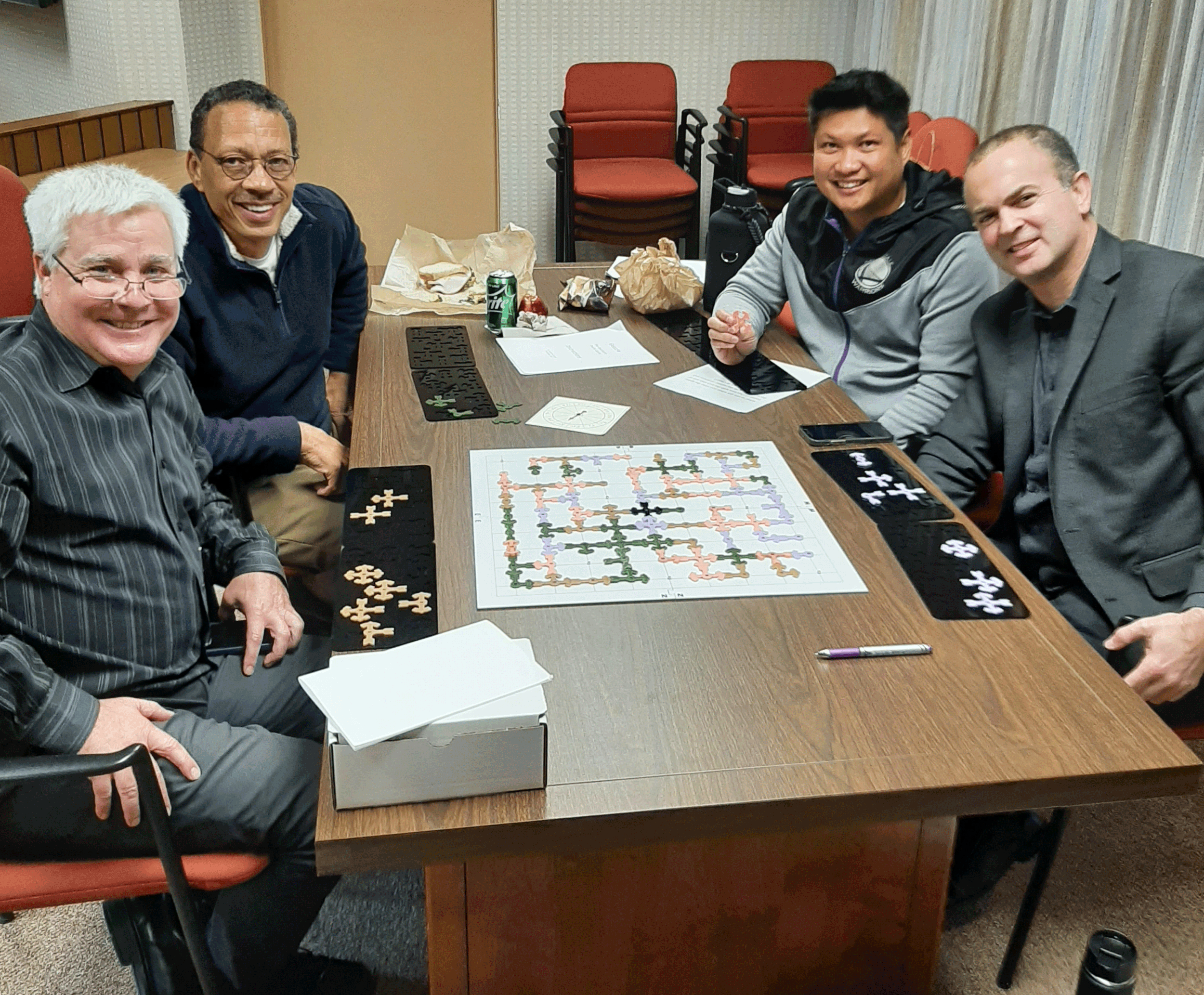 Four men sitting around a table playing GEOZZLE