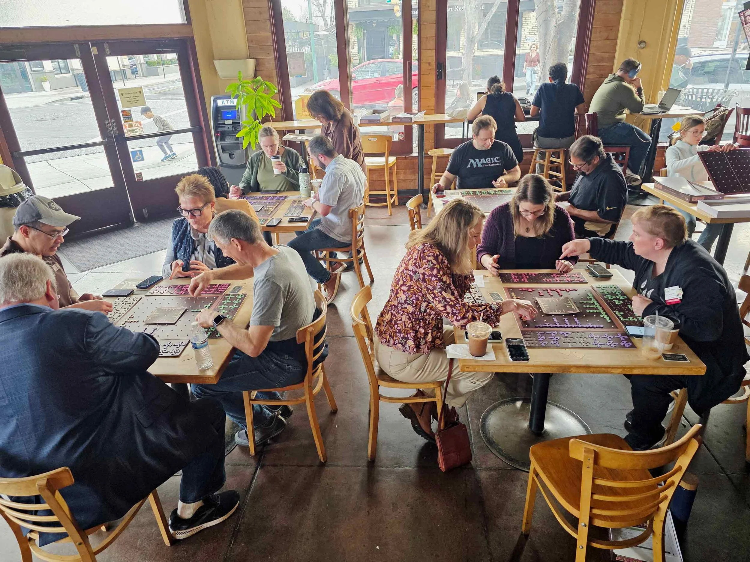 People sitting at tables inside a cafe or restaurant, playing GEOZZLE board games