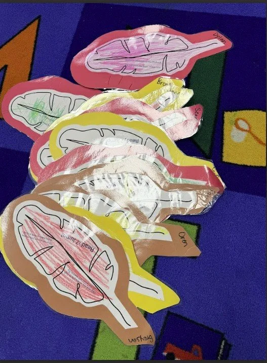Colorful paper cutouts of lips in pink, yellow, brown, and white, arranged on a purple and blue background.