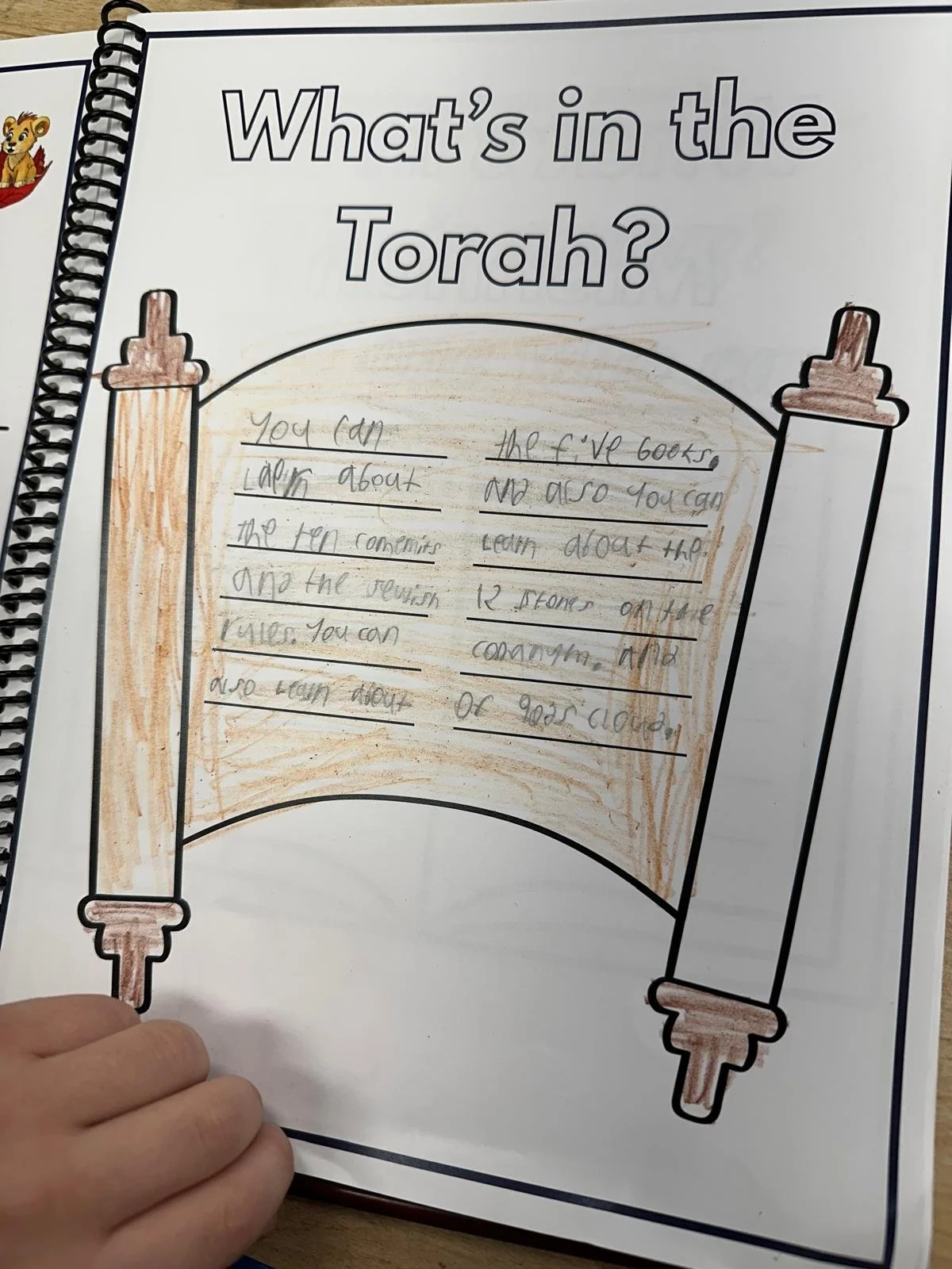 Colored drawing of a Torah scroll with handwritten notes inside, on white paper.