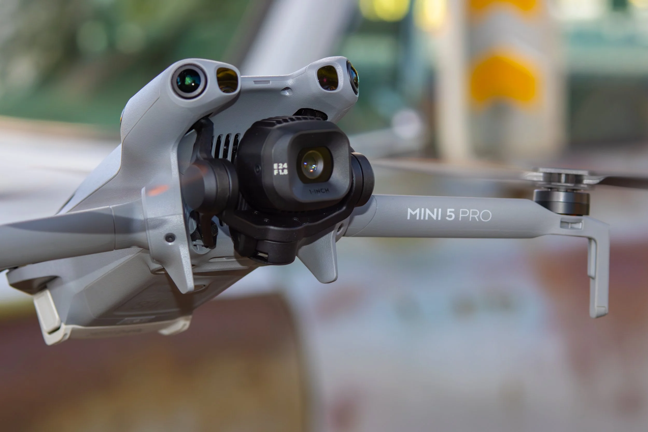 Close-up of a DJI Mini 5 Pro drone with camera, in an indoor setting with blurred background.