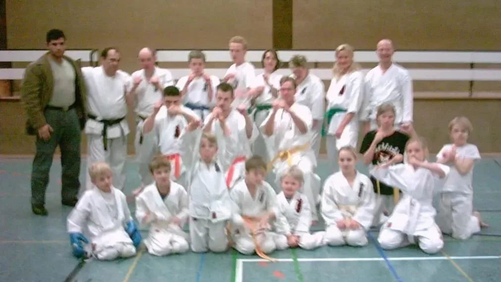 Gruppe von Kindern und Erwachsenen in Judogis in einer Kampfsportschule.