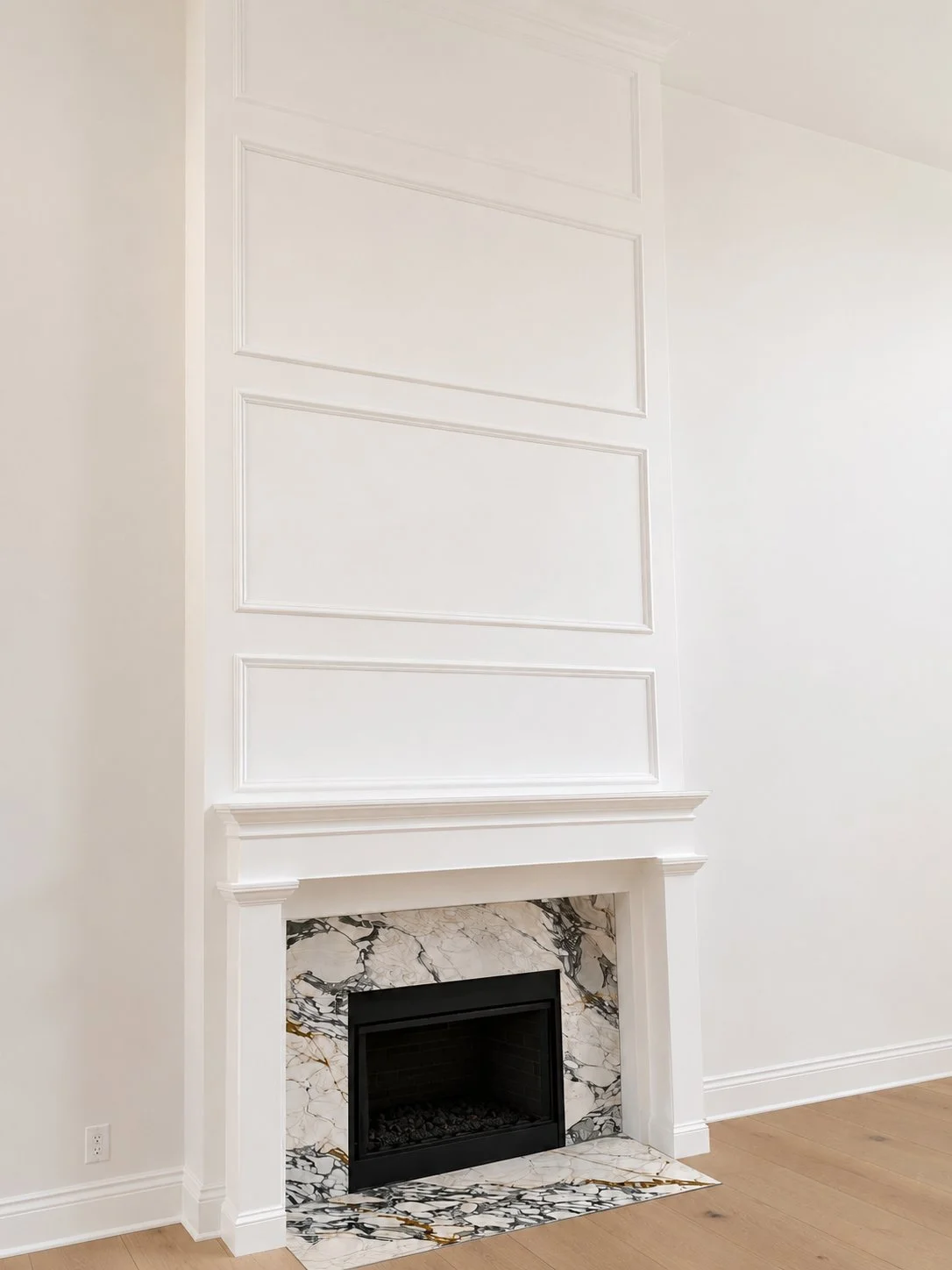 custom fireplace paneled wall to ceiling in great room all tied into custom built mantel with leg surround. Painted white.