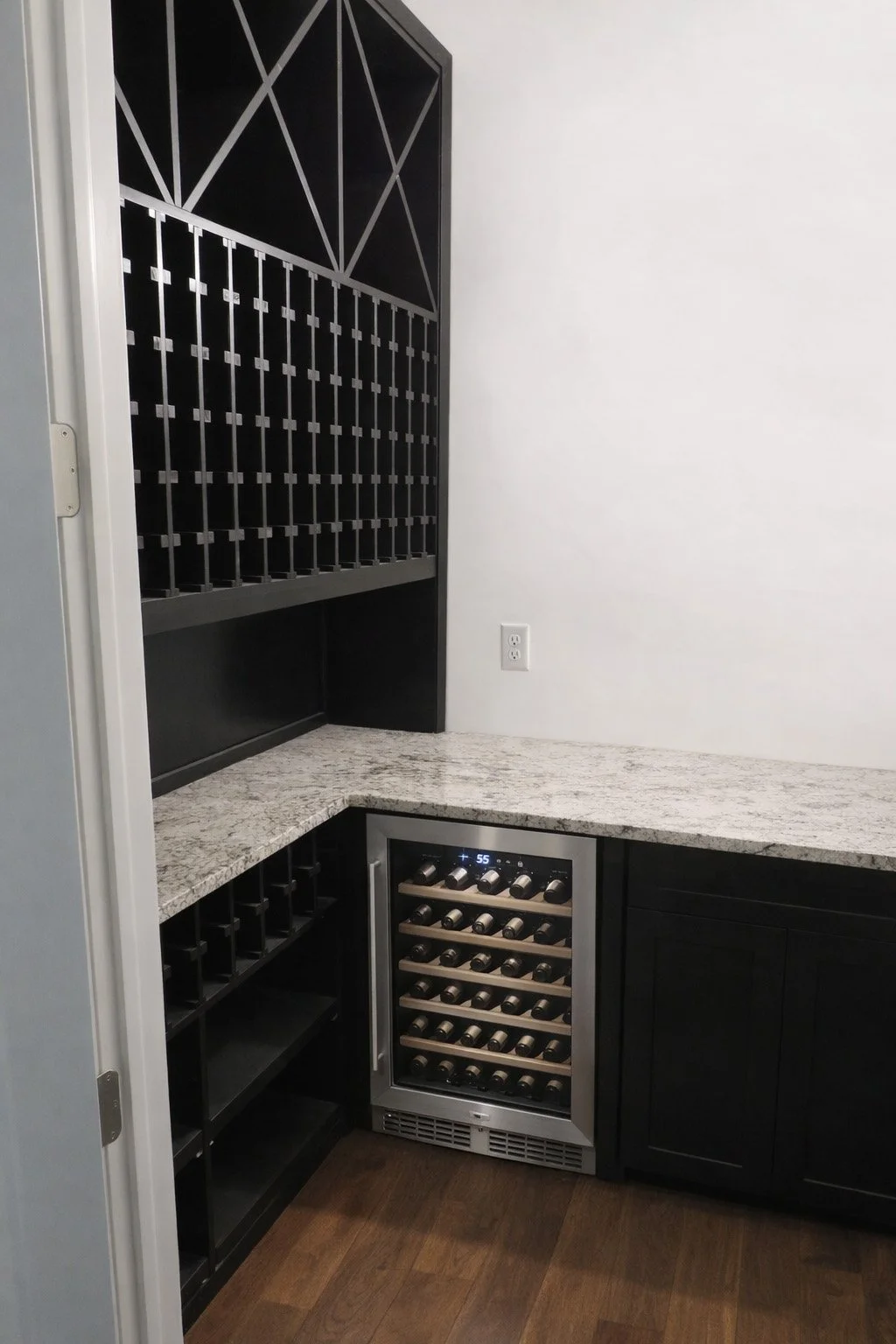 Custom built wine room cabinetry with a dark mocha stain and clear lacquer. Wine bottle dividers and wine bottle cubby system for storage. Lower pull outs for crated wines. Wine fridge built into sink cabinet wall area.