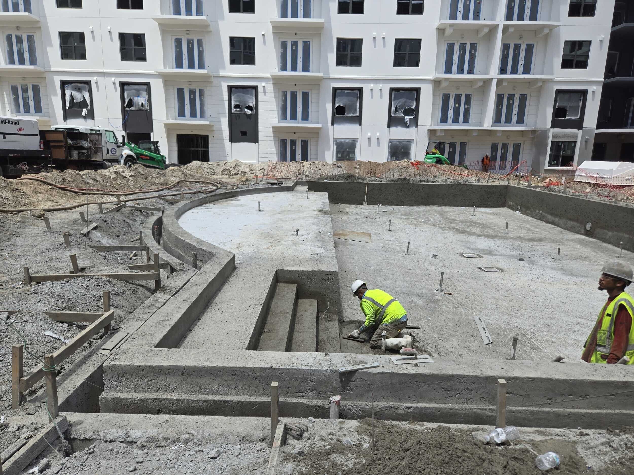 Elite Gunite workers shaping a large commercial pool for an apartment complex.