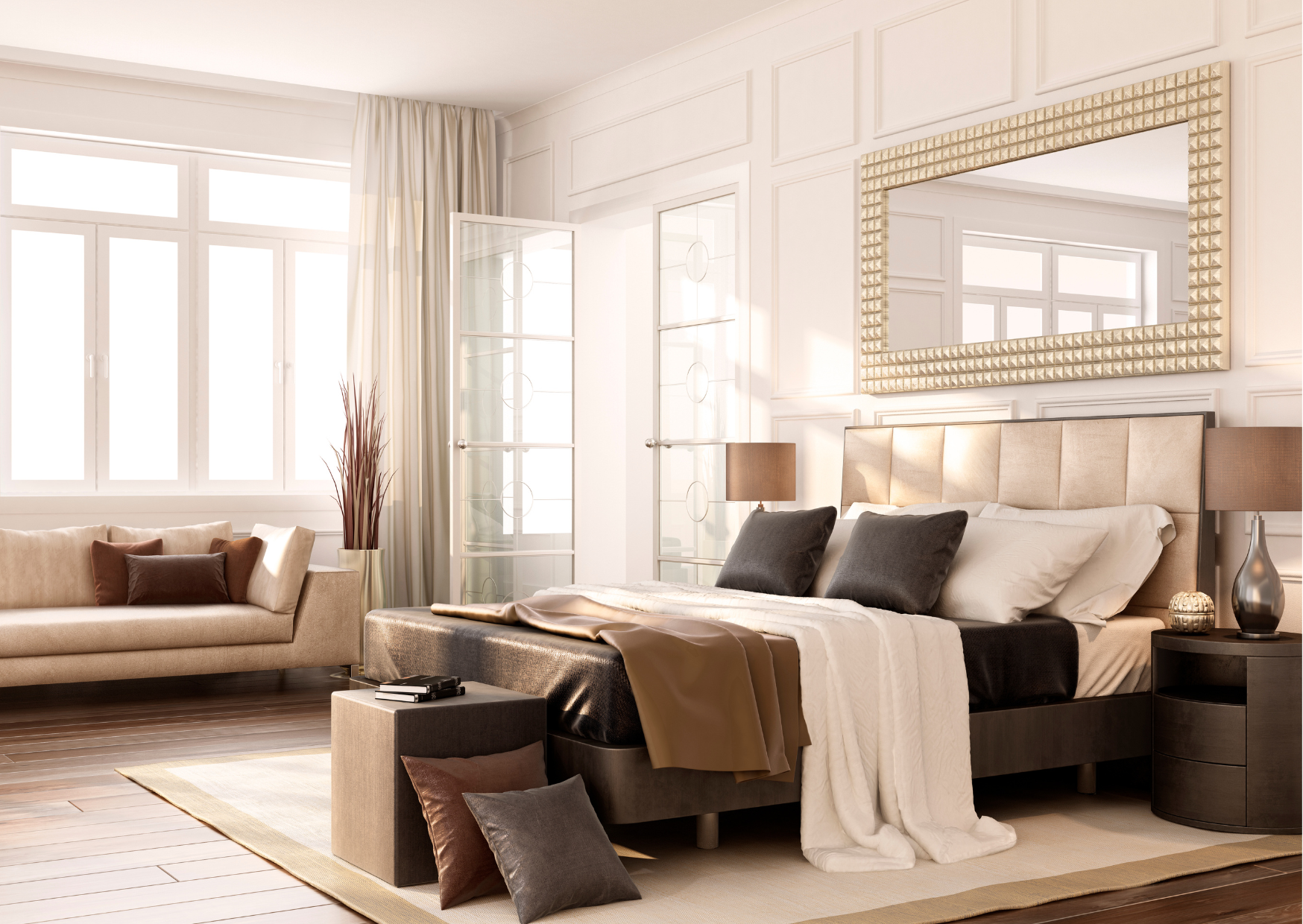 Bright bedroom with large window, beige sofa with brown pillows, bed with beige headboard, black pillows, and white and beige bedding, two nightstands with lamps, gold-framed mirror above bed, wooden floors, and decorative pillows.