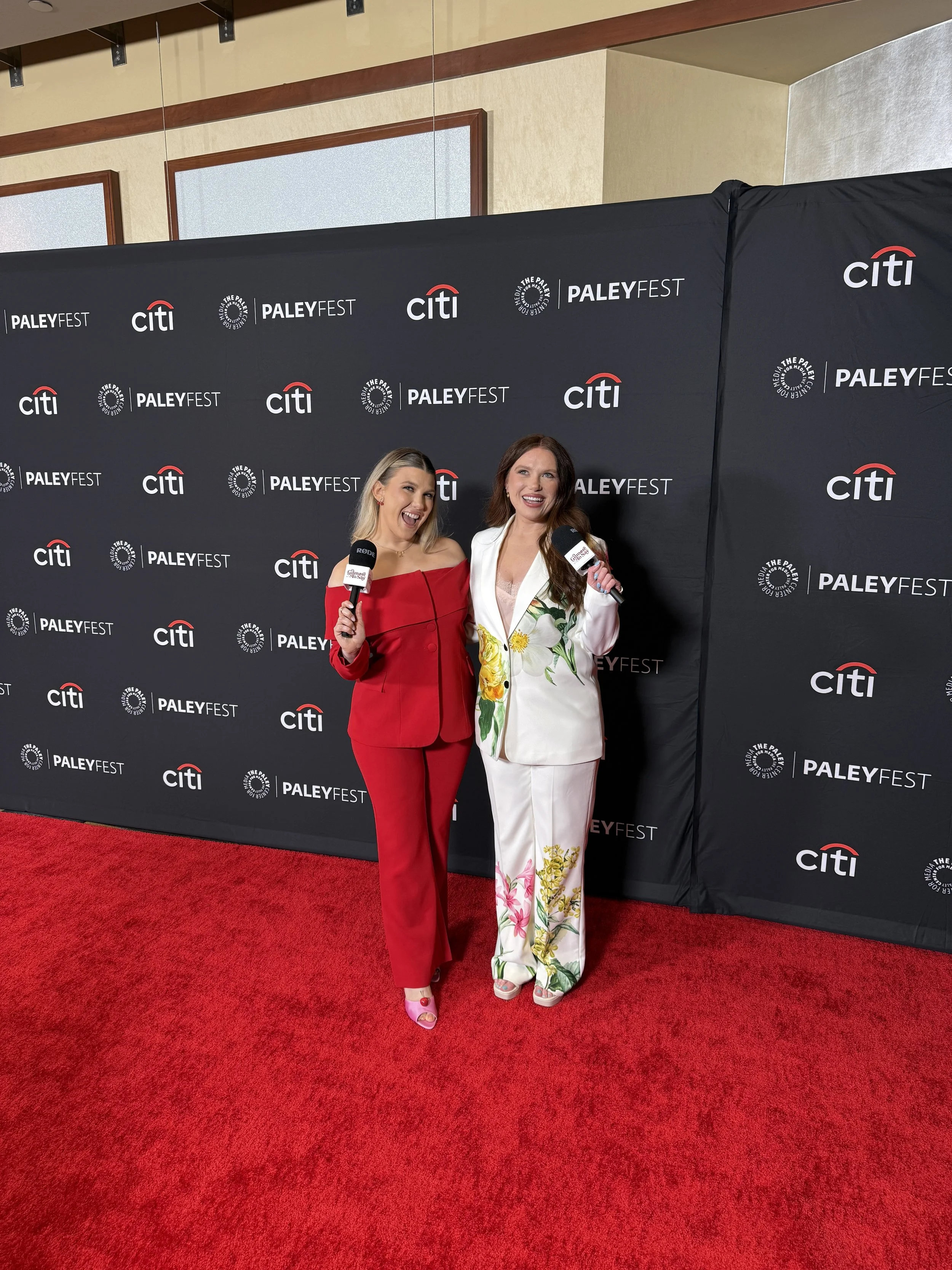 Two women standing on a red carpet at PaleyFest, smiling and holding microphones, in front of a black backdrop with PaleyFest, Citi, and The Paley Center logos.