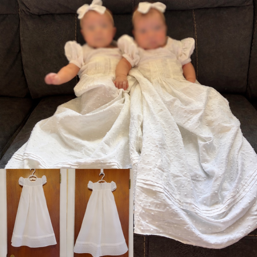 Two young girls with blurred faces wearing white dresses and bows on their heads, sitting on a dark couch, with matching long white dresses hanging on hooks in the background.