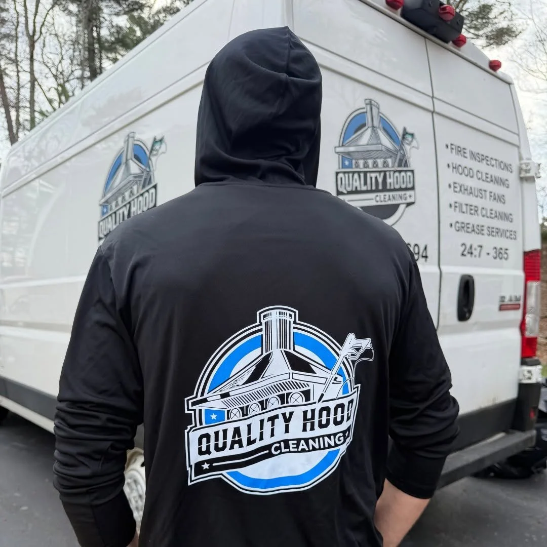 Person wearing a black hoodie with a 'Quality Hood Cleaning' logo on the back, standing in front of a white cleaning service van with similar branding and list of services.