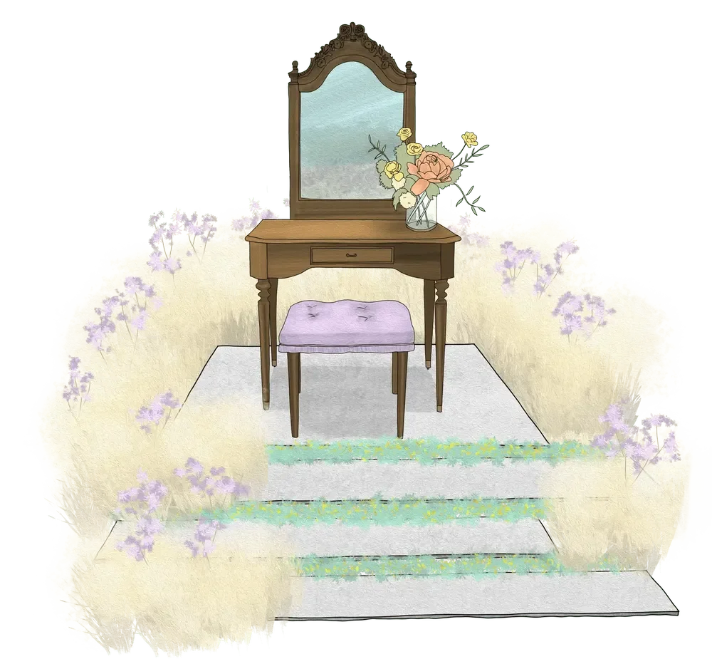 A vintage wooden vanity with a mirror and a small drawer, topped with a vase of pink and yellow flowers, is positioned on a white rug in front of a flower-covered area with lavender blossoms.