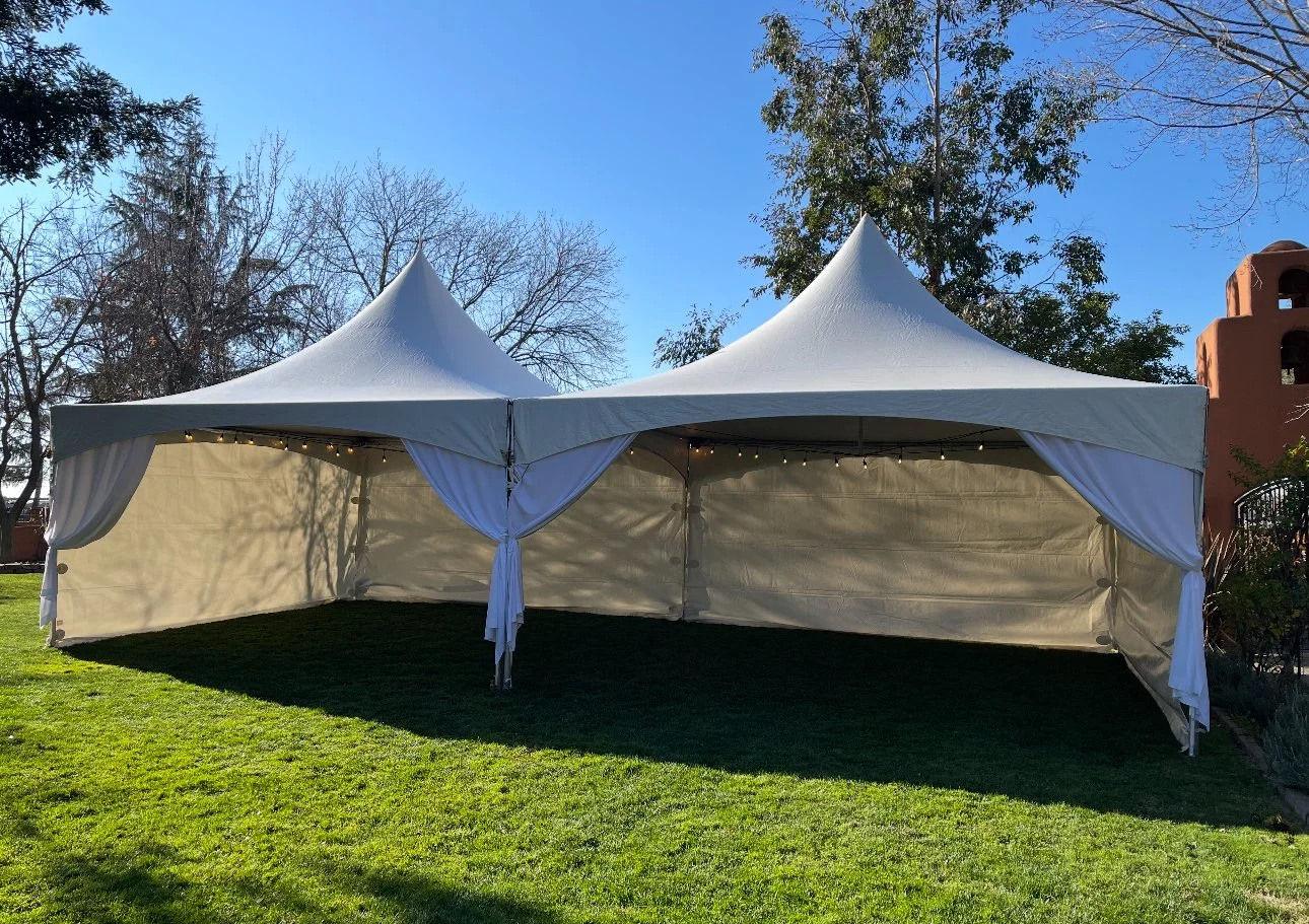 Tent rental for an outdoor event with lights and decorations at sunset.