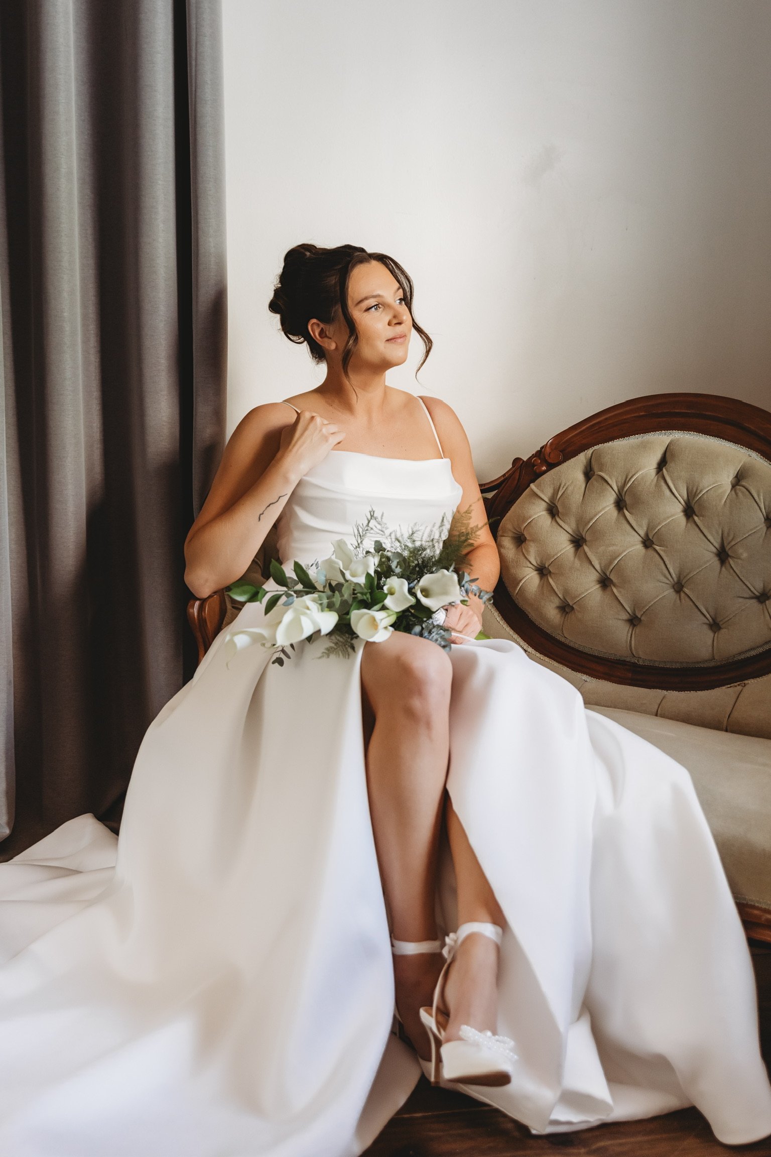 Bride seated on a vintage sofa wearing a white wedding dress holding a floral bouquet in Palm Beach, FL | Shelby Eve Photography