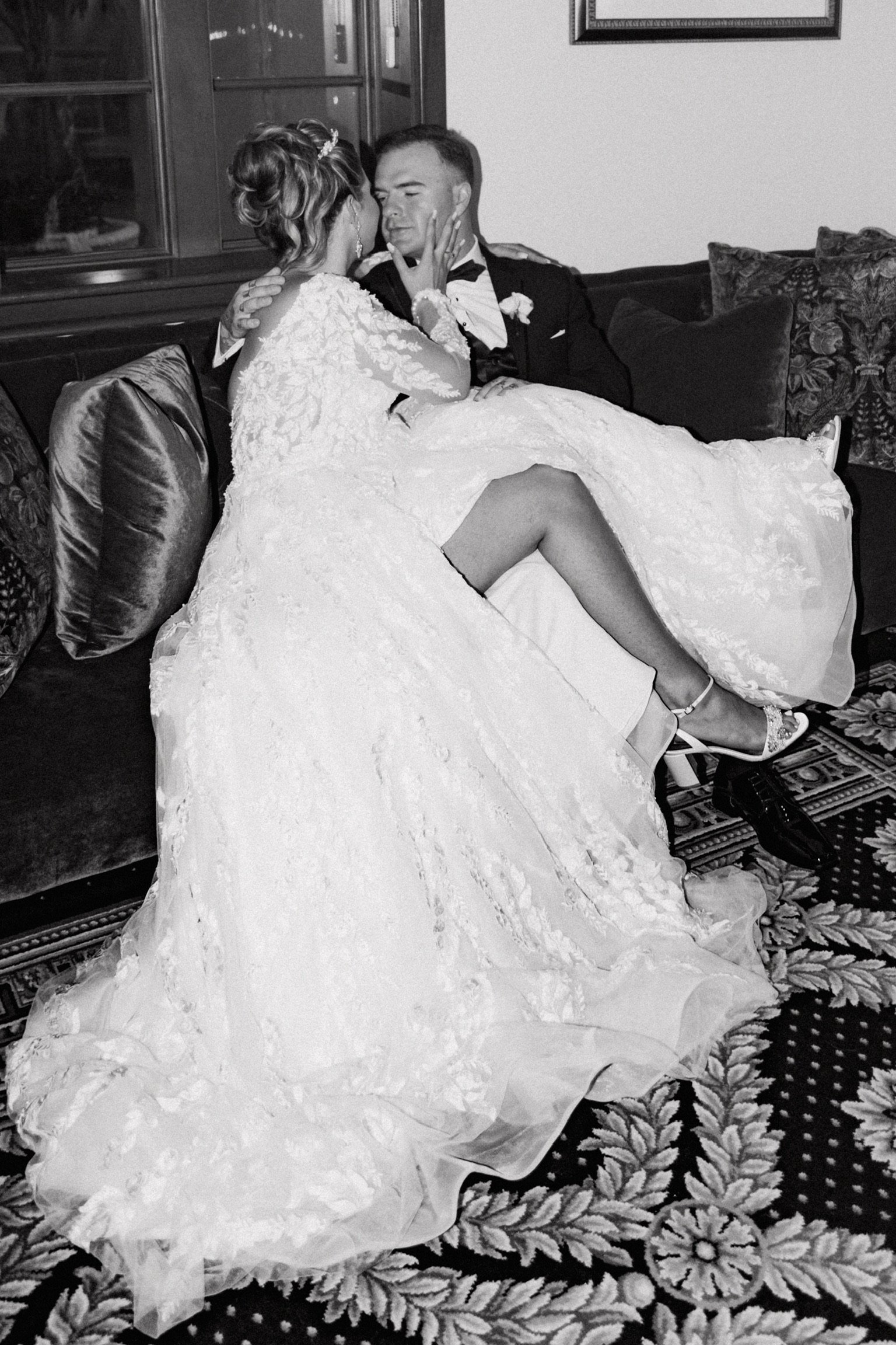 Bride and groom sitting on a couch in wedding attire sharing an intimate moment in Palm Beach, FL | Shelby Eve Photography