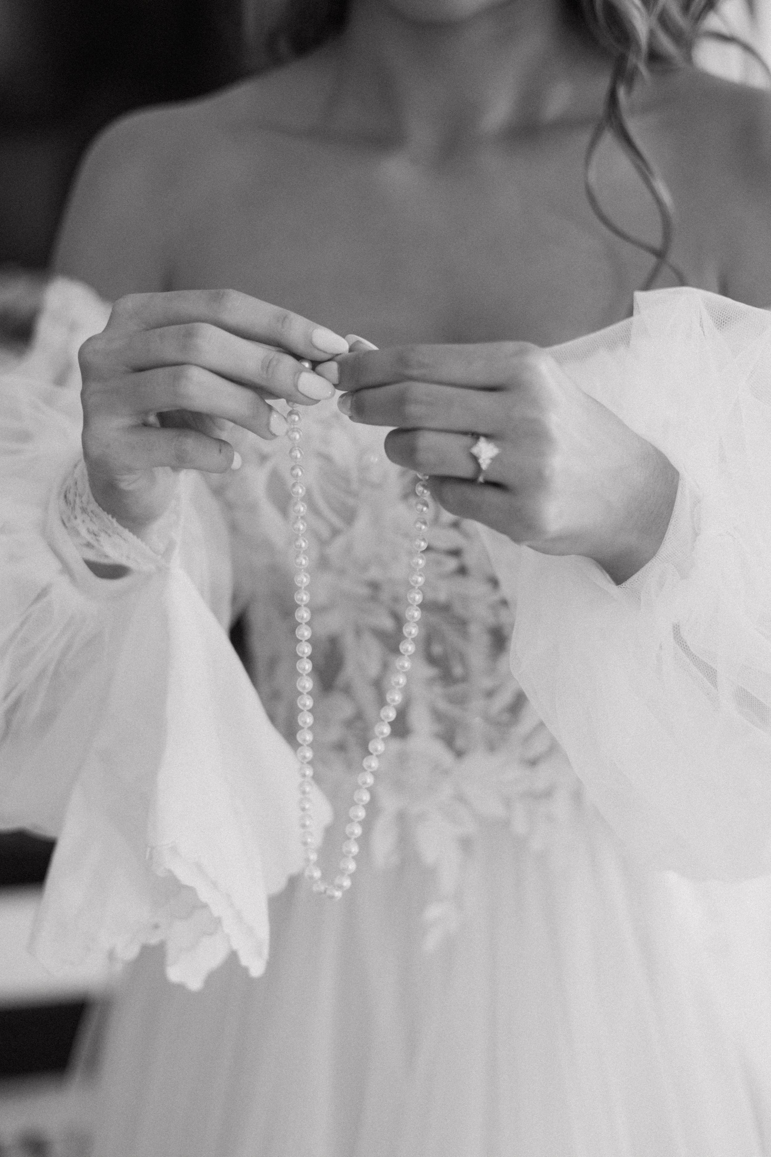 Bride holding pearl necklace, wearing lace wedding dress, close-up in Palm Beach, FL | Shelby Eve Photography