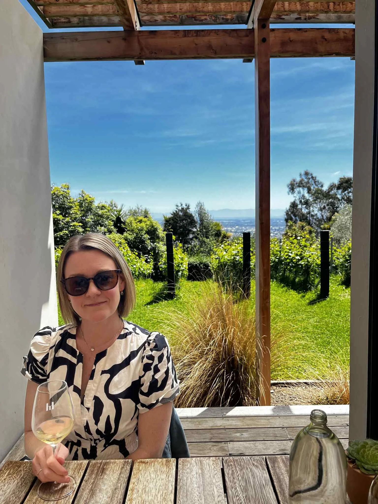 Female coaching client with blonde hair is smiling at the camera on a bright Summer's day.