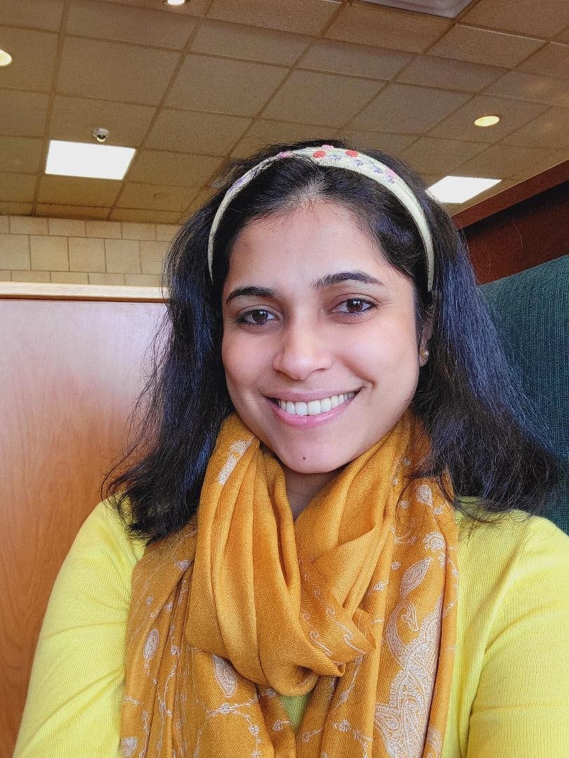 Headshot of Alex's previous coaching client who is smiling at the camera, wearing a bright yellow scarf.