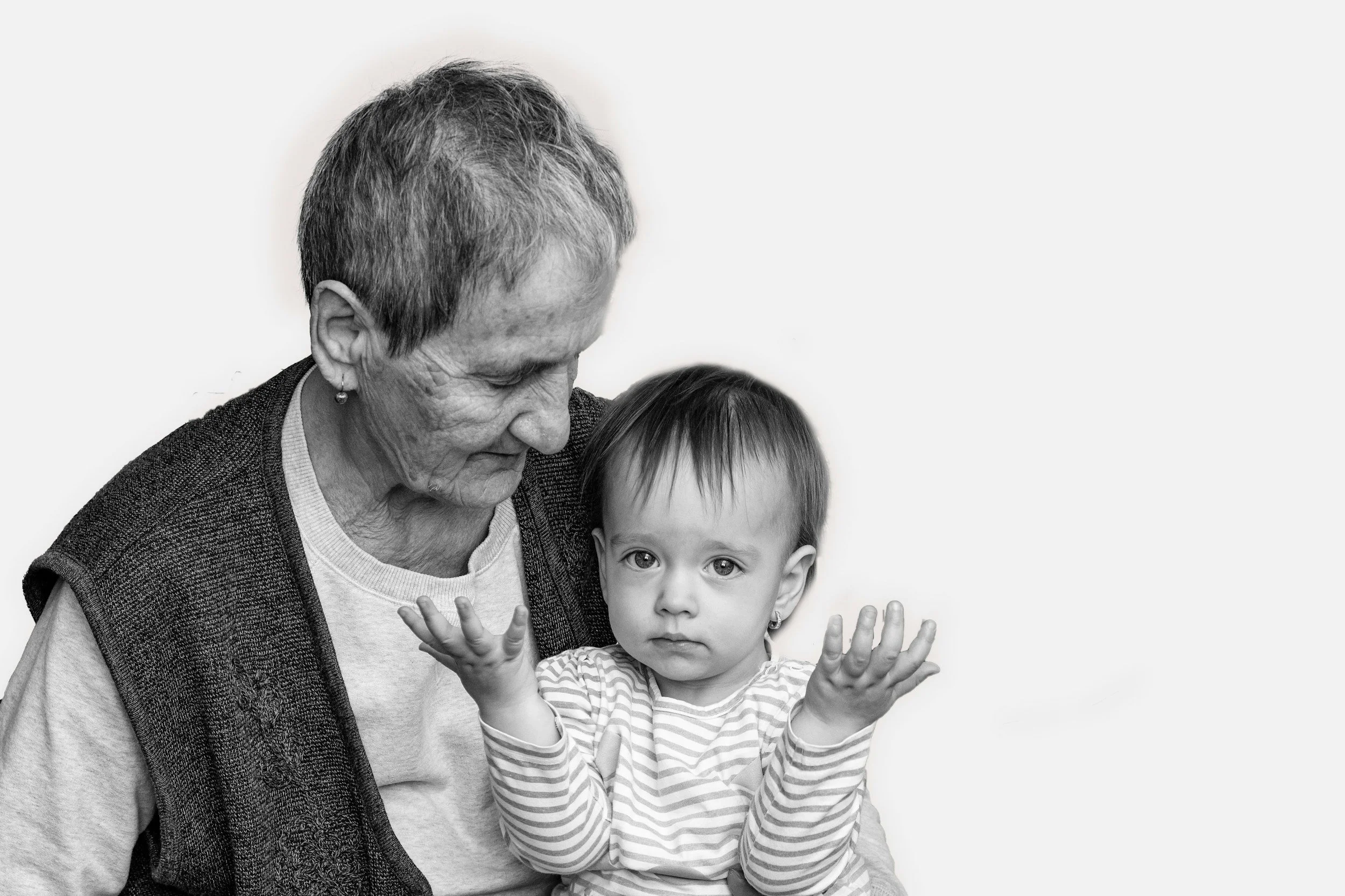 An elderly woman holding a young girl with her hands raised, confused by Aged Care, both looking at the camera in a black-and-white photograph.