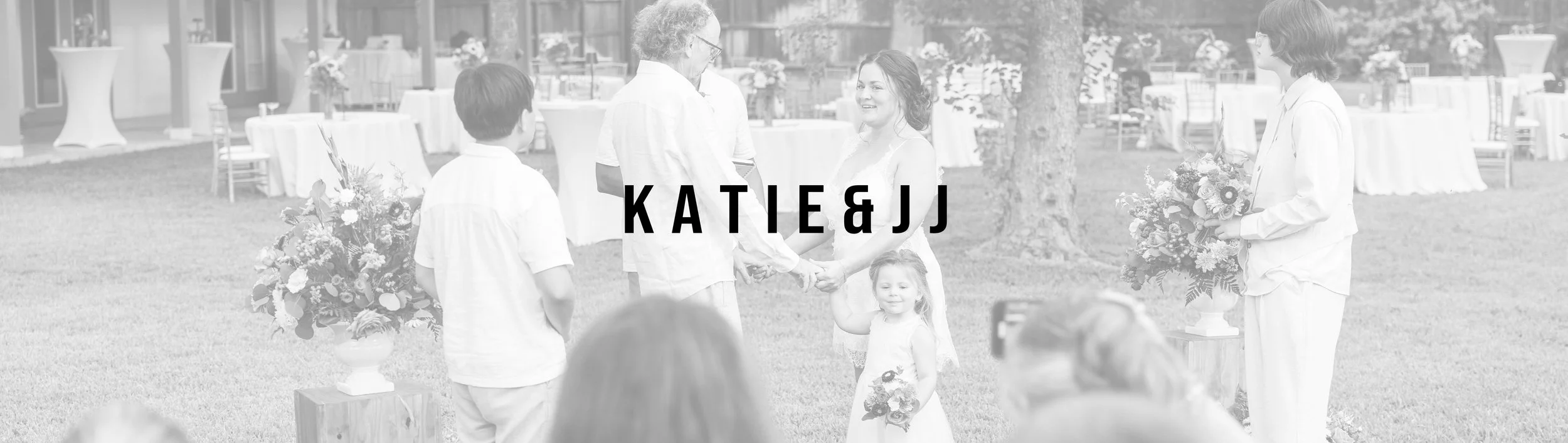 A wedding ceremony taking place outdoors with the bride and groom holding hands, surrounded by family members. The bride holds a bouquet, and the groom is dressed in a white suit. The scene features floral arrangements and tables in the background.