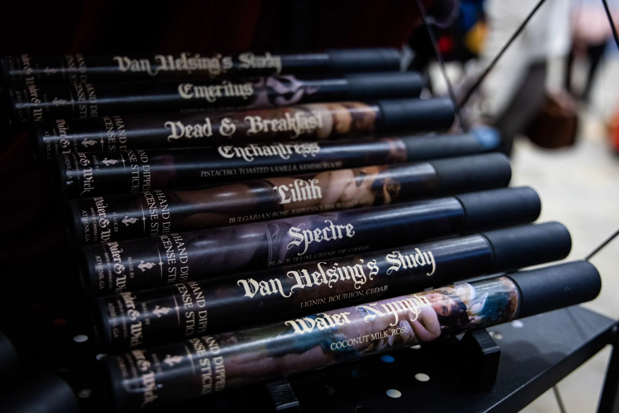 A collection of fragrance tubes with various labels and designs, arranged in a rack.